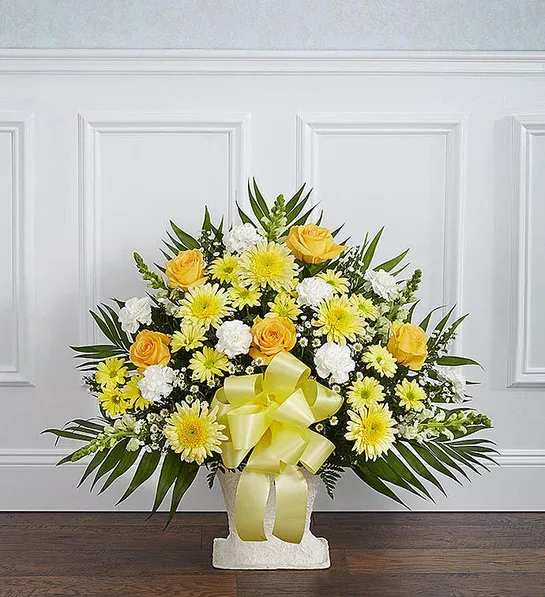 Yellow and white floral arrangement with a ribbon in a white vase