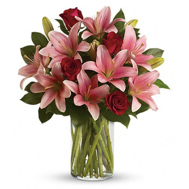 Pink lilies and red roses arranged in a clear glass vase