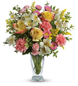 Mixed bouquet of roses, lilies, and carnations in a clear glass vase