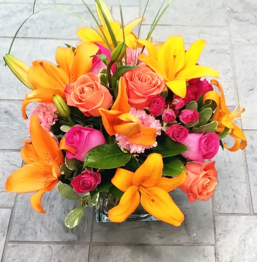 Bright bouquet of orange lilies and pink roses in a glass vase