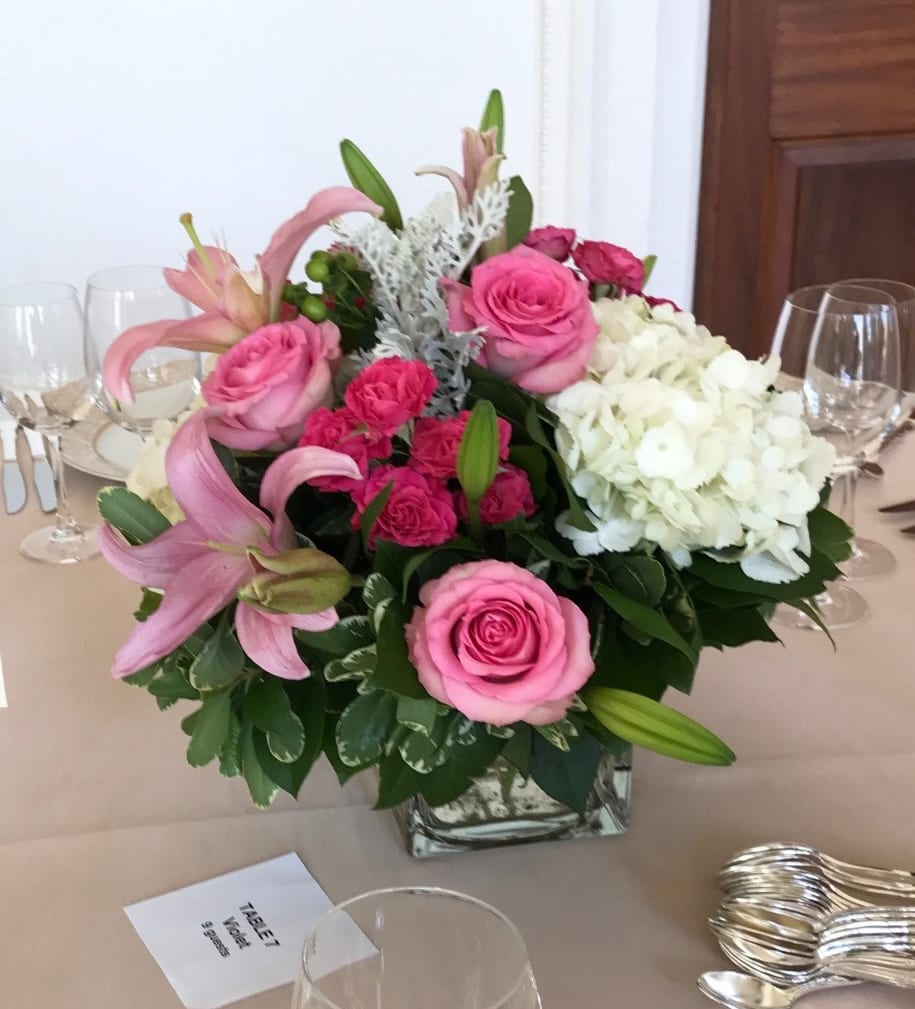 Pink roses and lilies arranged with white hydrangeas in a square glass vase