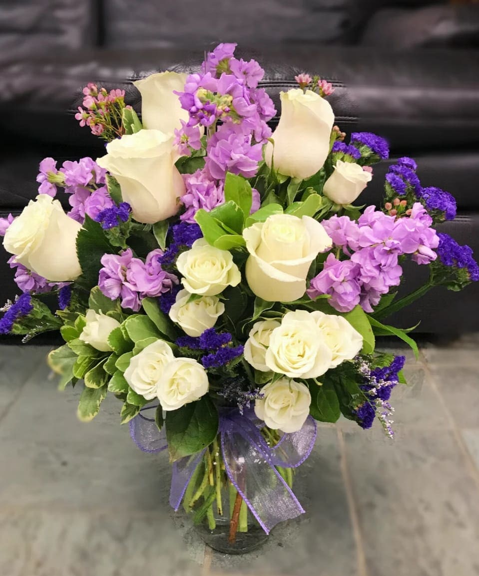 Bouquet of white roses and purple flowers in a glass vase