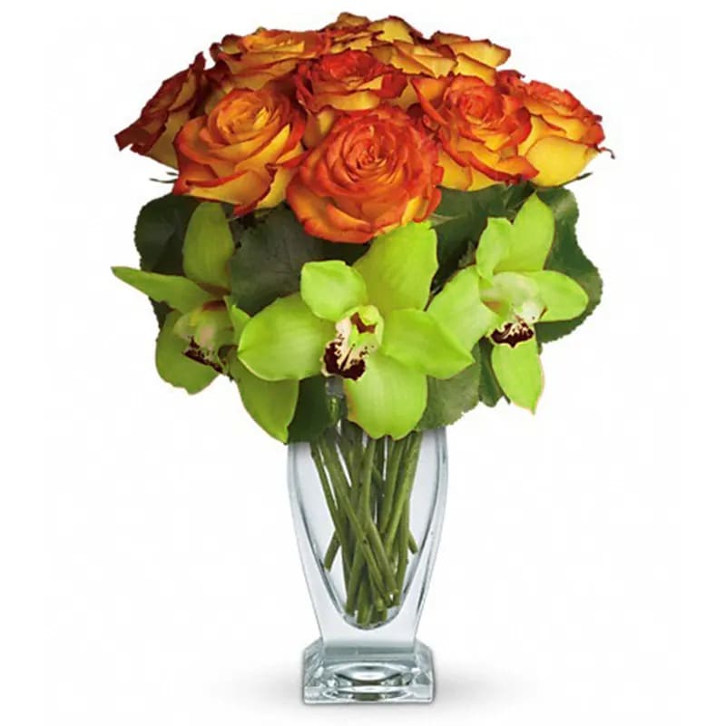 Bouquet of orange and yellow roses with green orchids in a clear glass vase