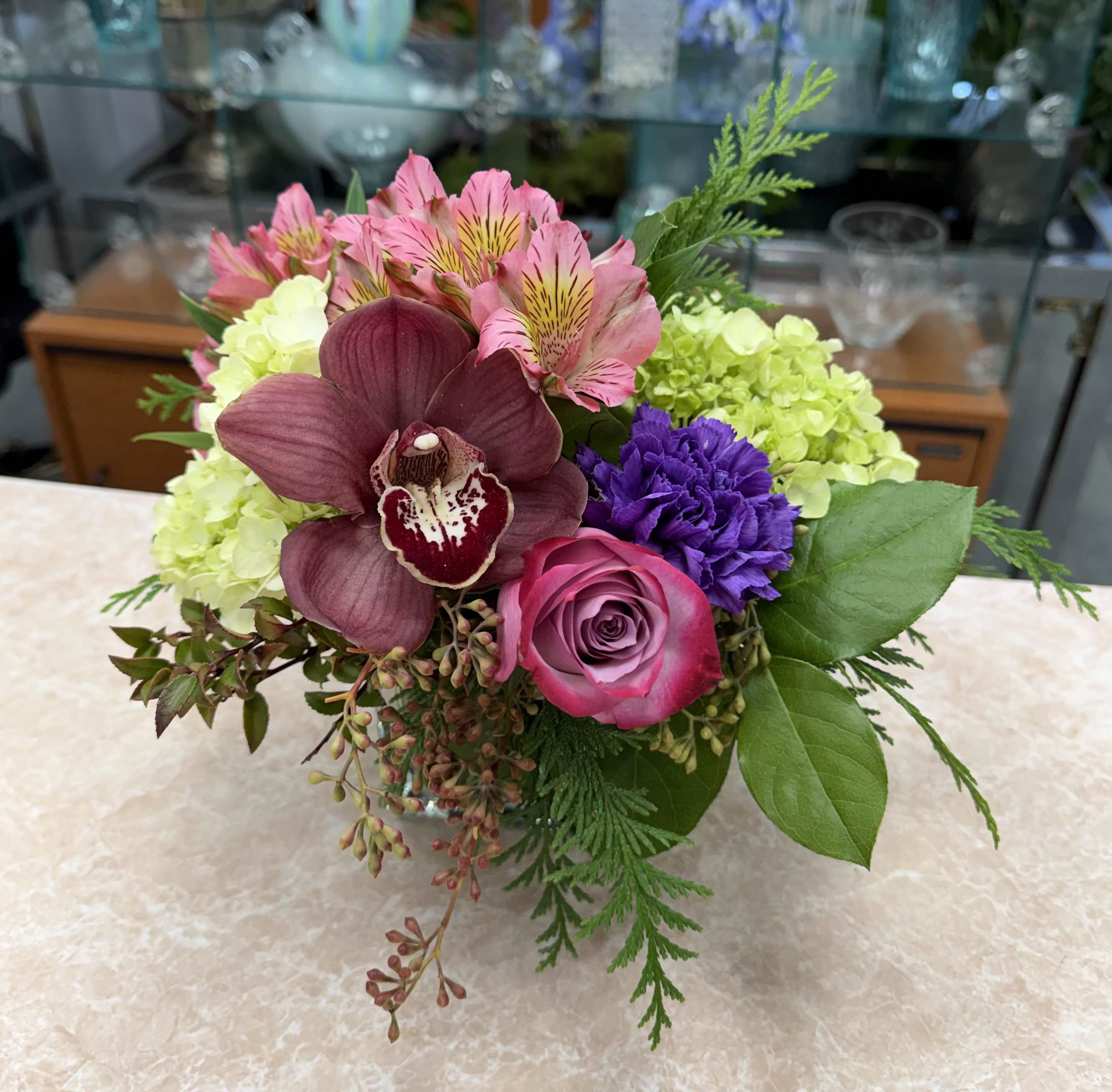 Mixed bouquet with pink, purple, and green flowers in a low vase