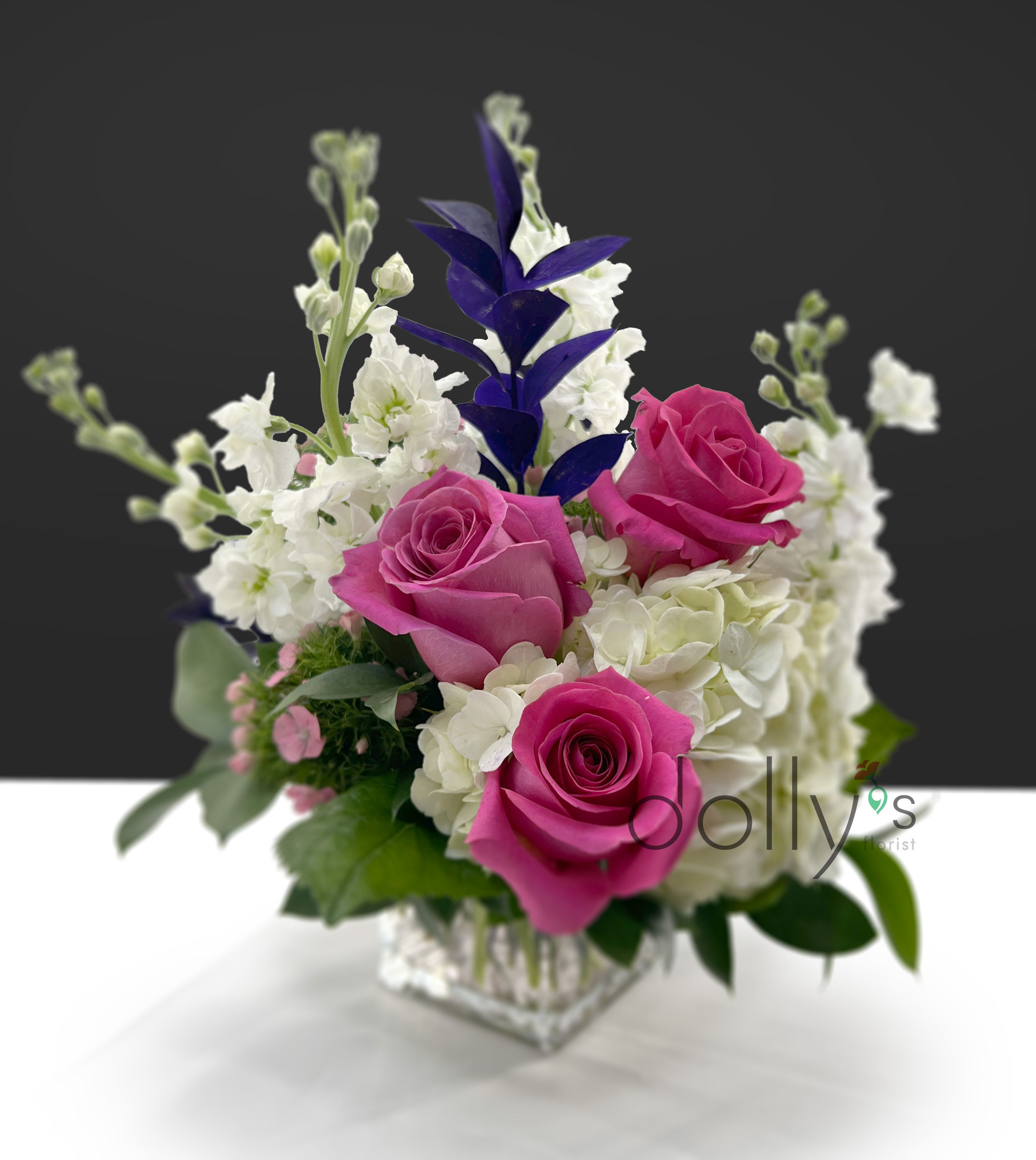 Pink roses and white flowers arranged in a clear square vase