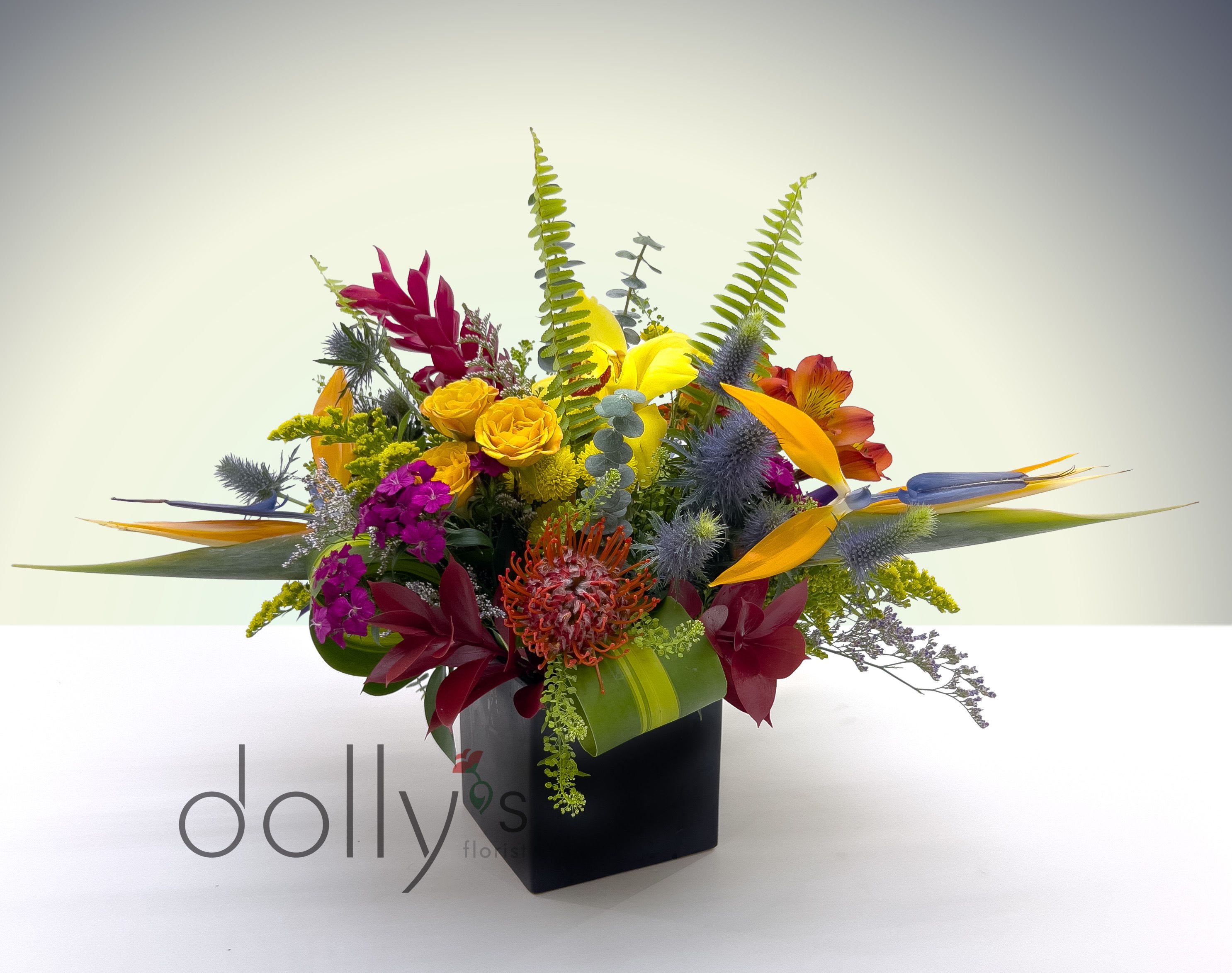 Tropical flower arrangement in a black cube vase with bright mixed blooms