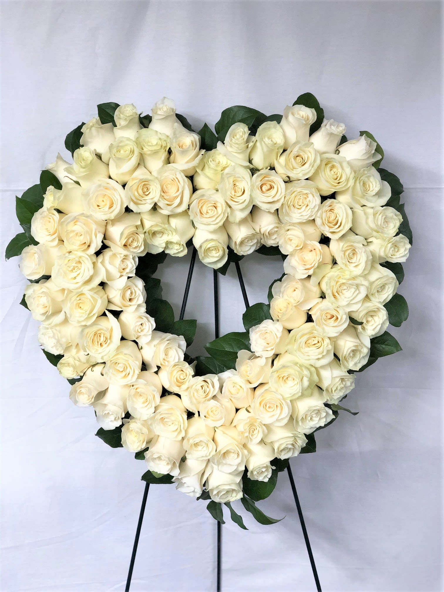Heart-shaped wreath of white roses on a stand