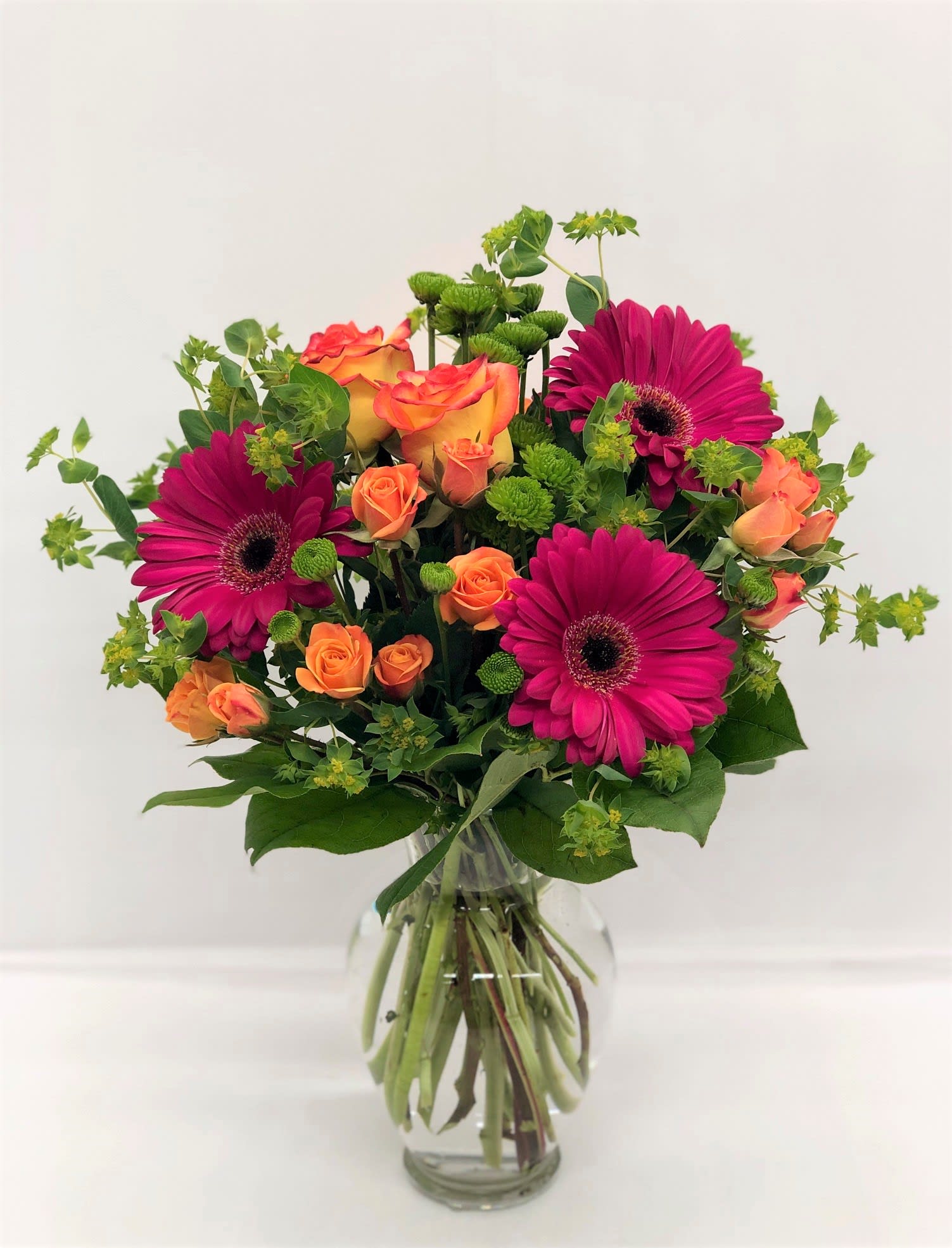 Bouquet of magenta gerbera daisies and orange roses in a glass vase