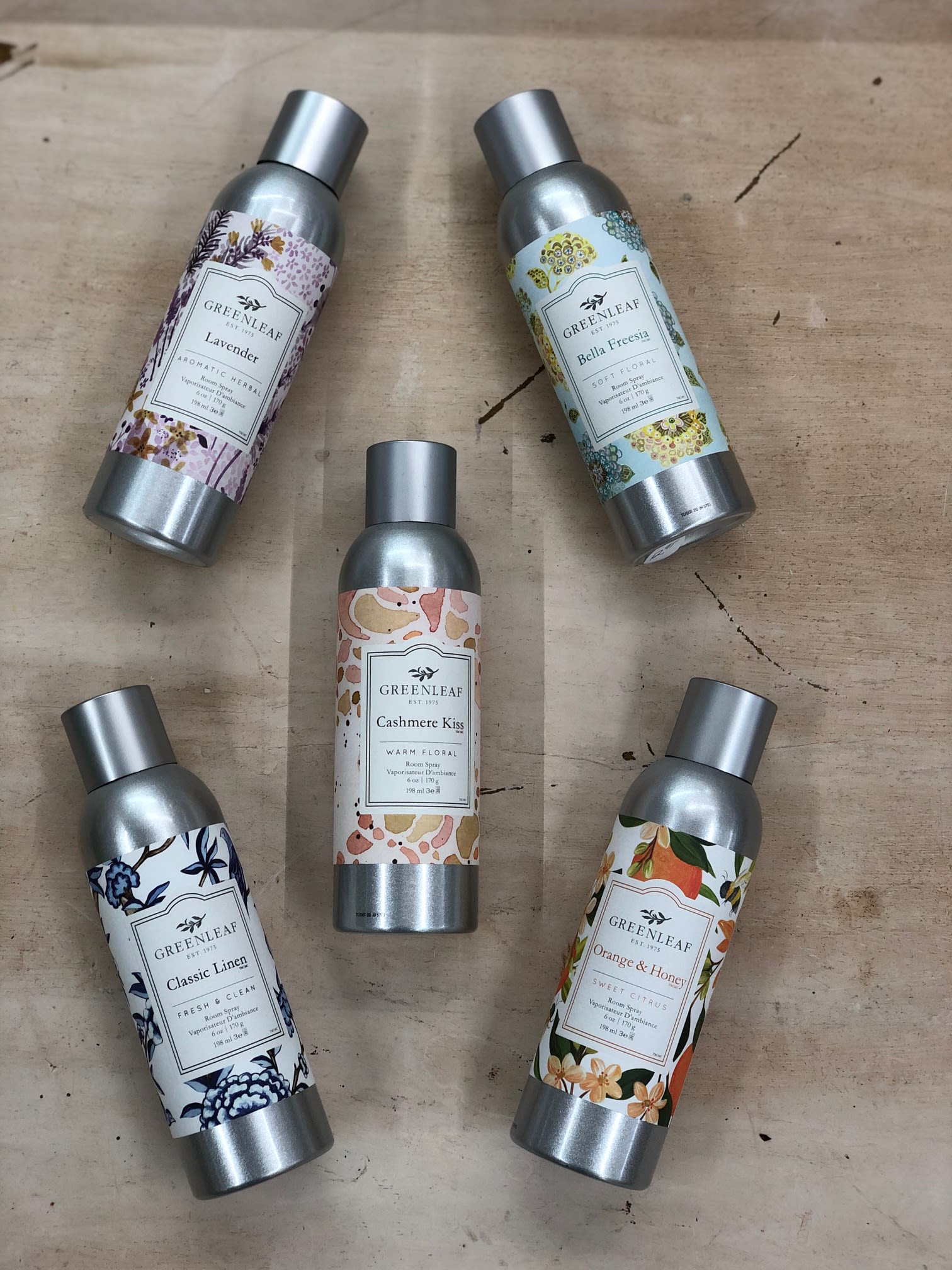 Set of five Greenleaf scented room spray bottles arranged on a wood surface