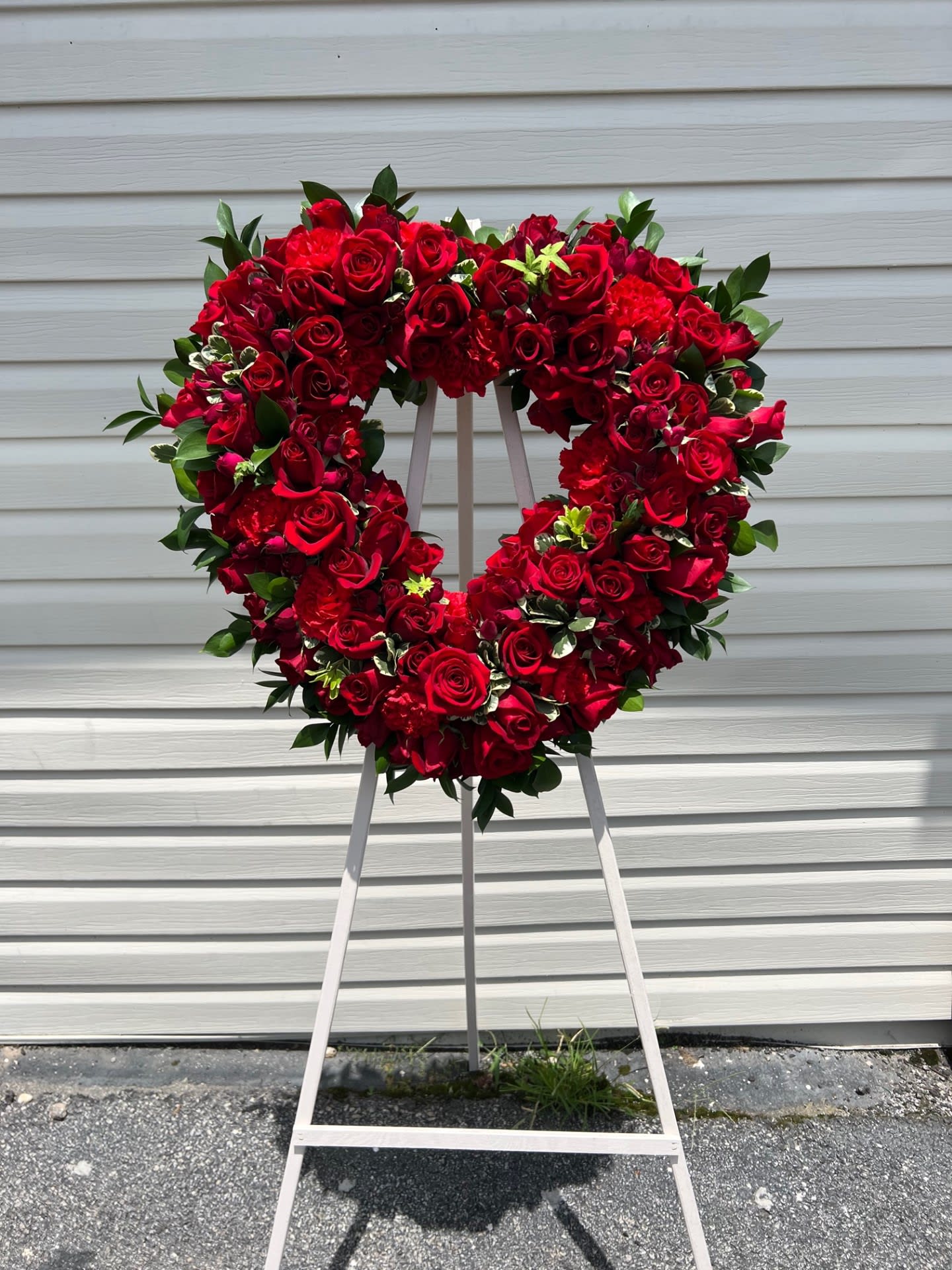 Heart-shaped red rose wreath on a standing easel