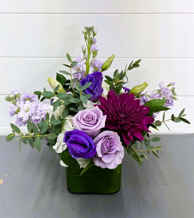 Purple and lavender flowers arranged in a green vase