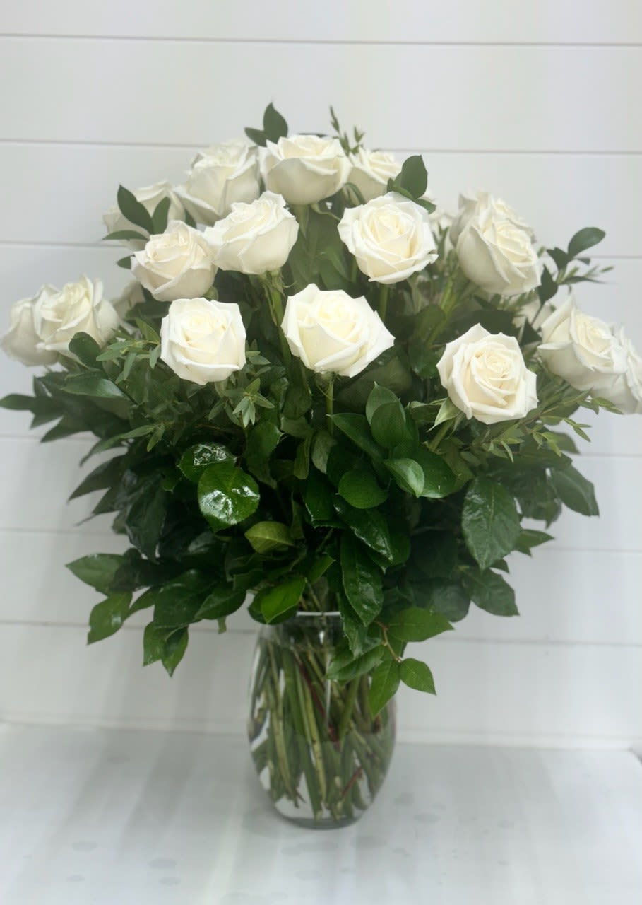 Tall arrangement of white roses in a clear glass vase