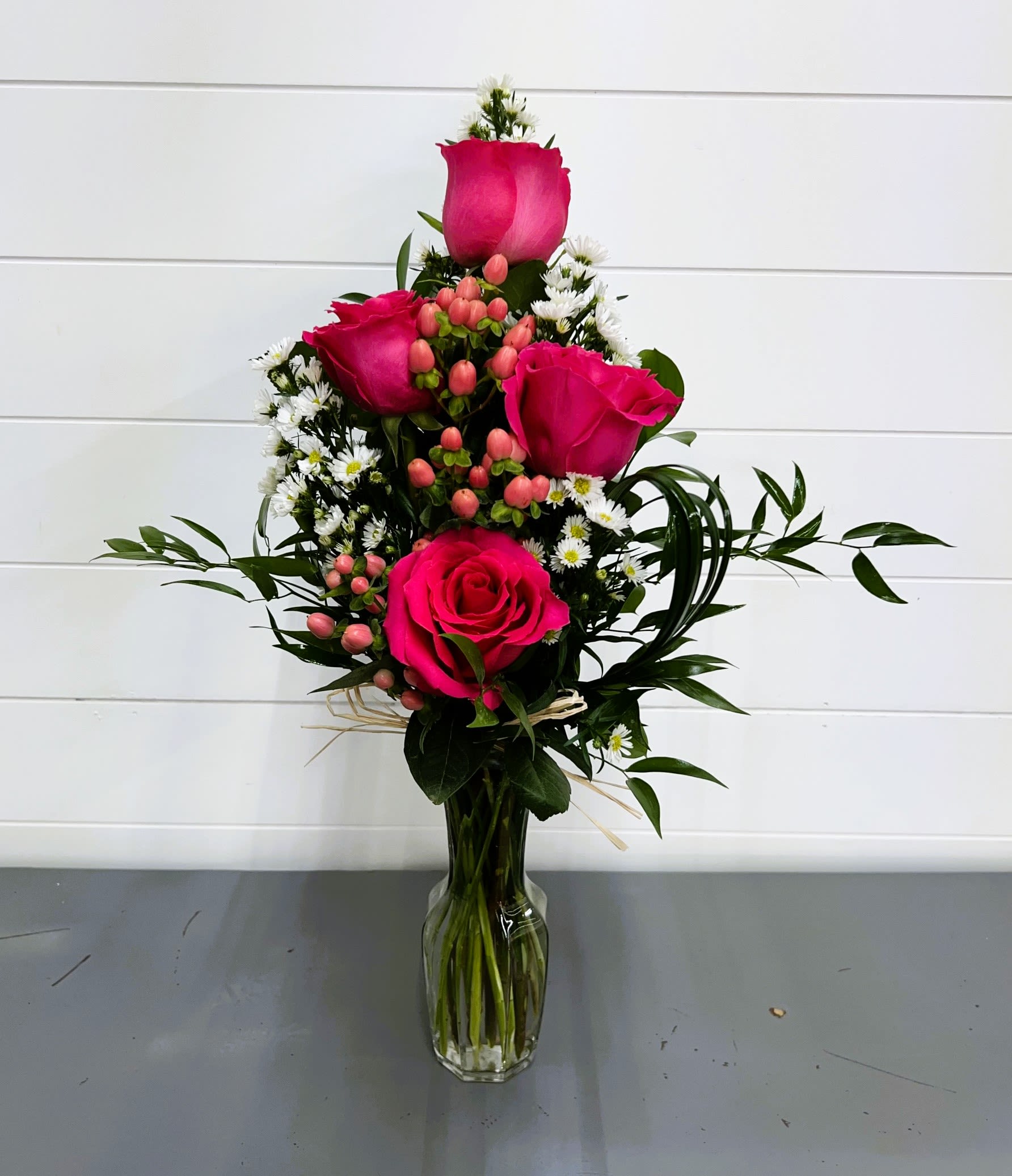 Pink roses and small white daisies in a clear glass vase