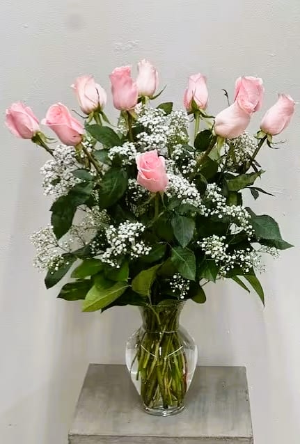 Pink roses arranged in a clear glass vase with white filler flowers