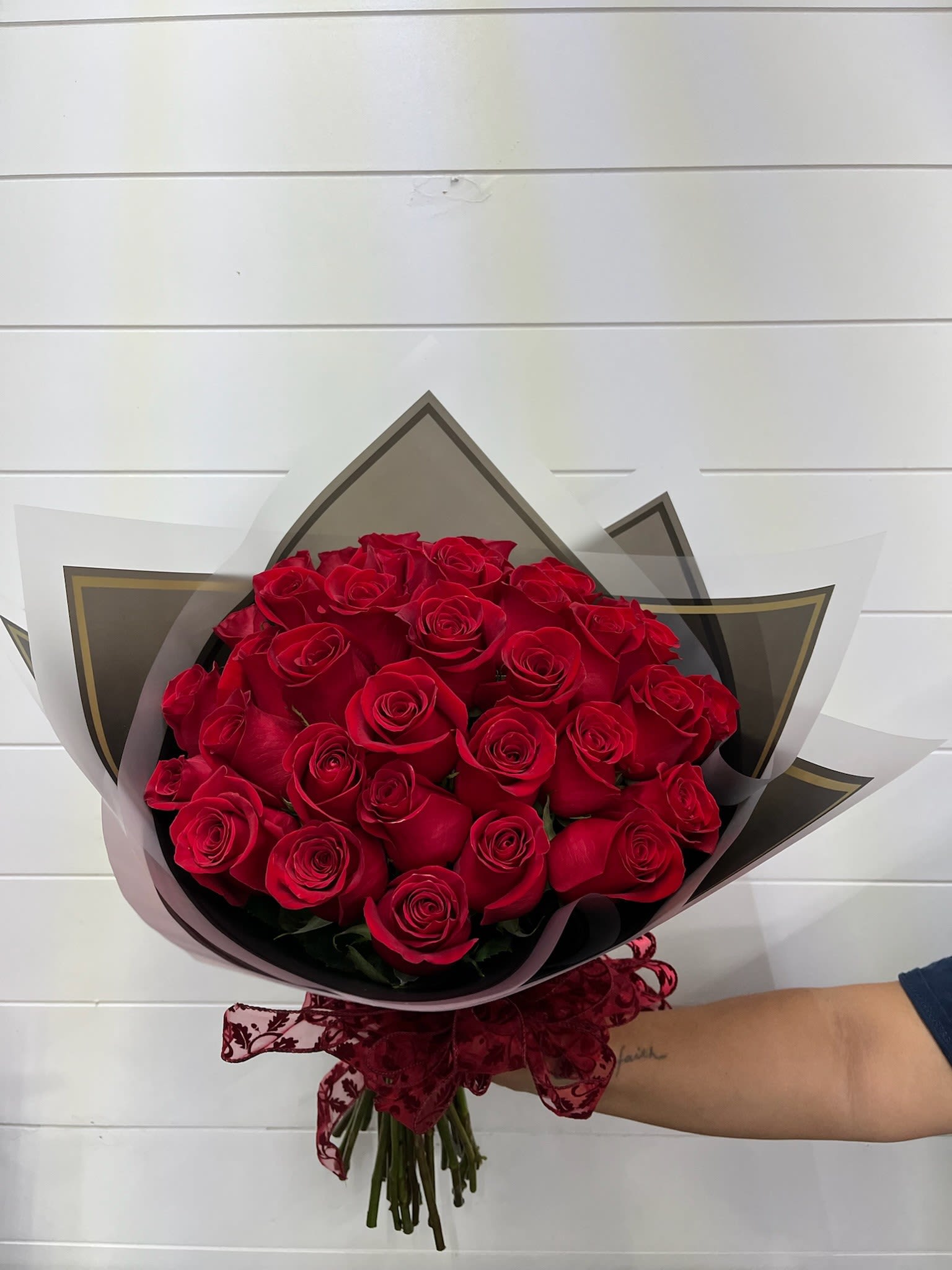 Bouquet of red roses wrapped in black and white paper with a burgundy ribbon