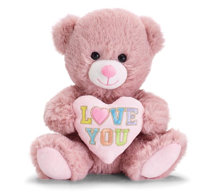 Pink plush teddy bear holding a pastel heart pillow with the words LOVE YOU.