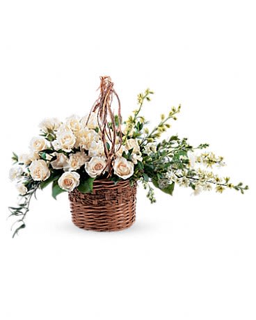 Cream roses arranged in a wicker basket with trailing greenery