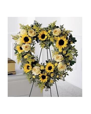 Heart-shaped floral wreath with sunflowers and cream roses on an easel