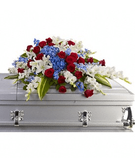Red roses, white lilies, and blue flowers arranged on a gray casket