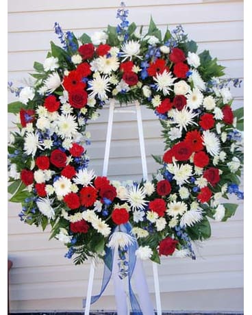 Large red, white, and blue floral wreath on a stand with ribbon