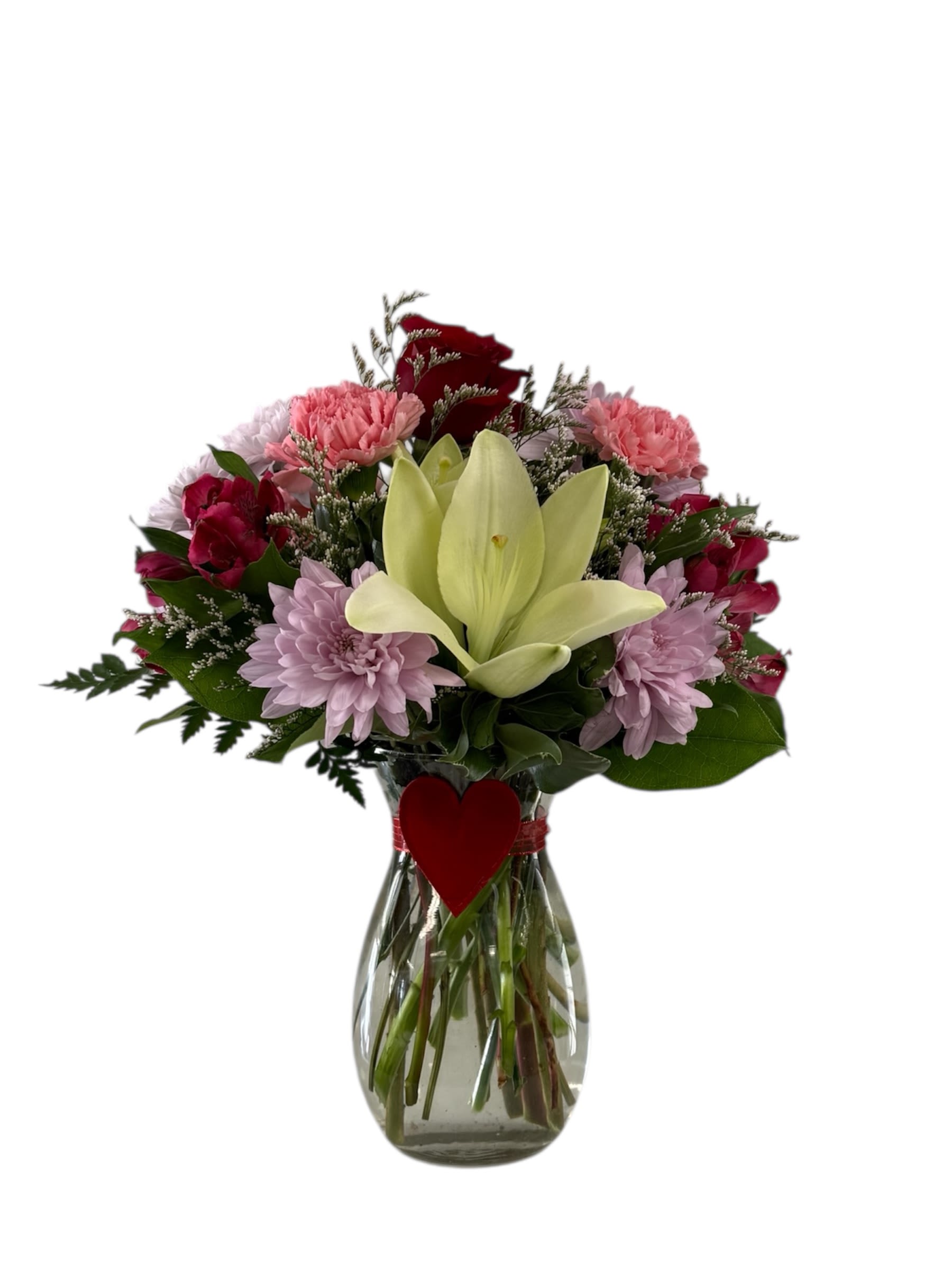 Bouquet of mixed pink and red flowers in a glass vase with a heart tag