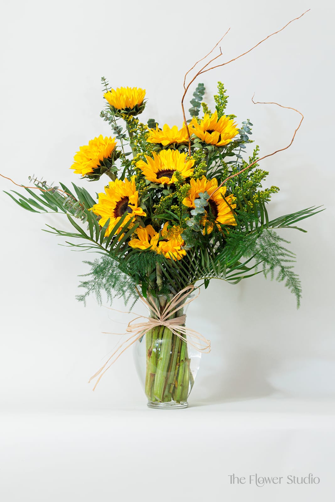 Sunflower arrangement in a clear glass vase with airy greenery