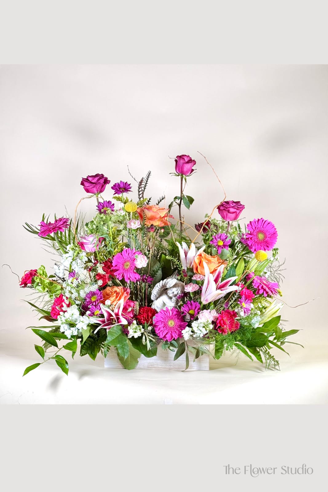 Mixed pink and orange floral arrangement in a white container