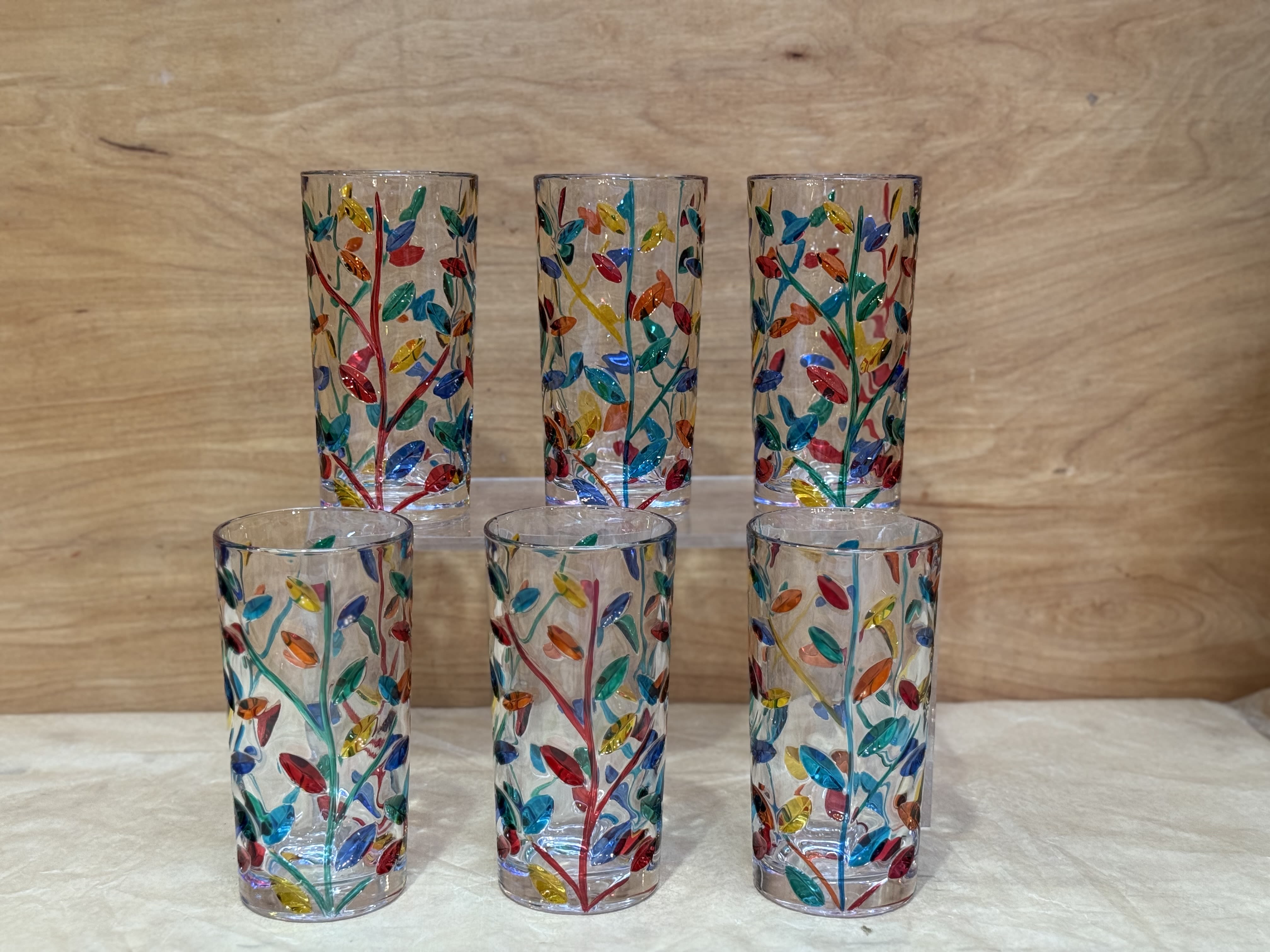 Six clear glass tumblers with colorful leaf patterns