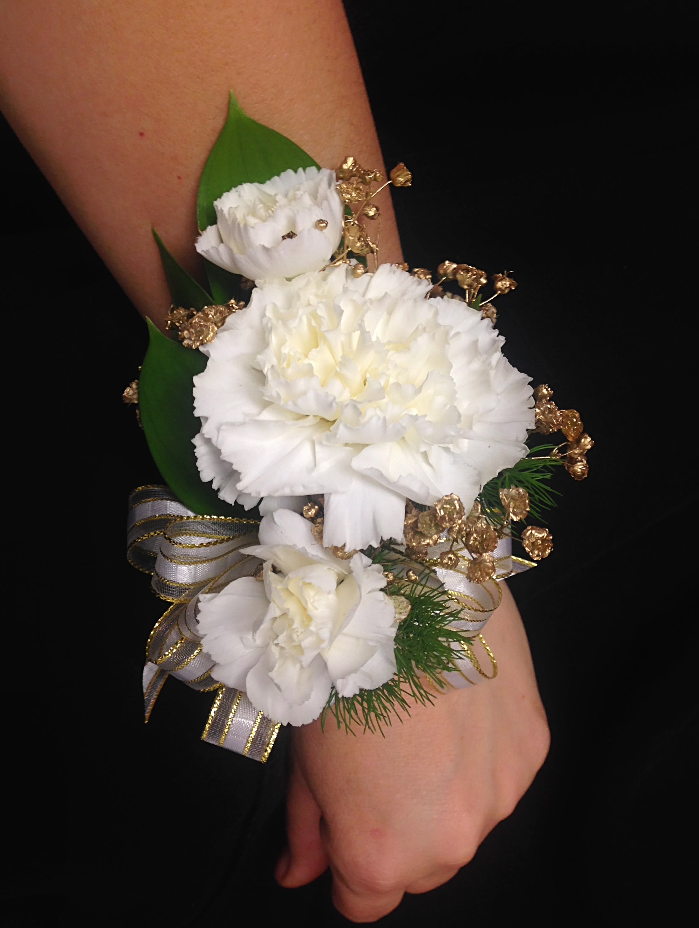White carnation wrist corsage with gold accents and ribbon