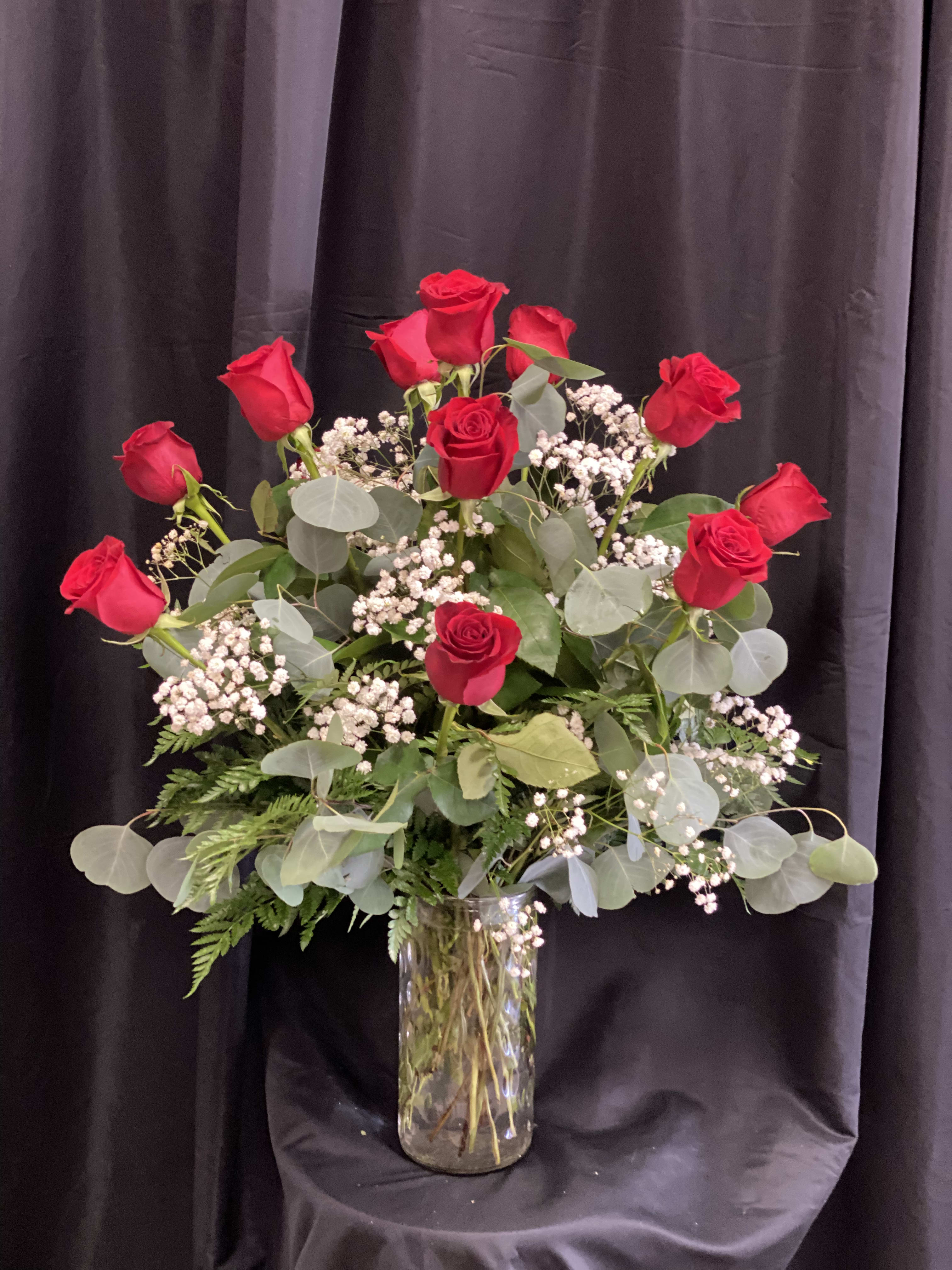 Red roses arranged in a clear glass vase with baby's breath