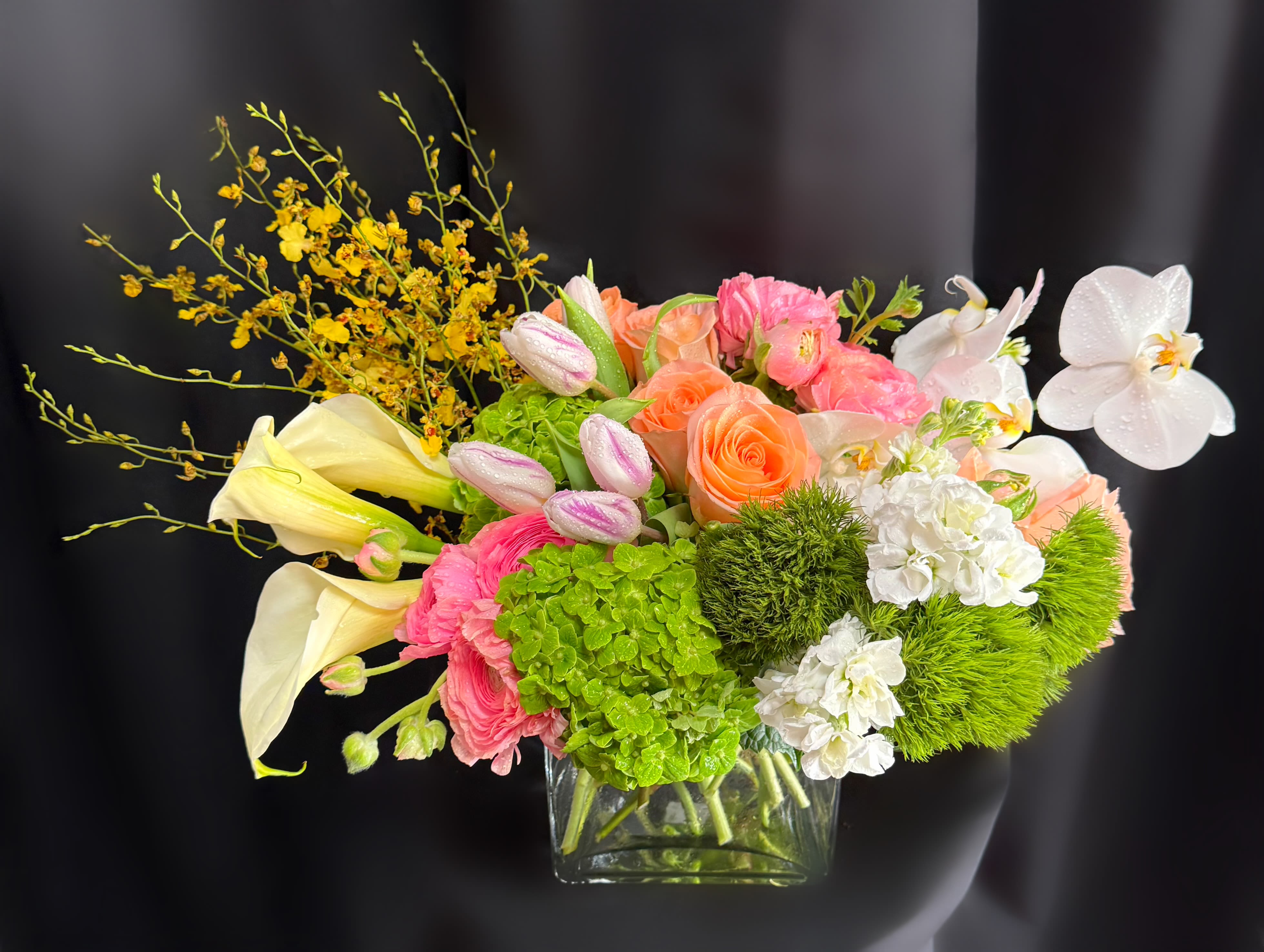 Mixed bouquet in a clear glass vase with pink, peach, white, and yellow flowers