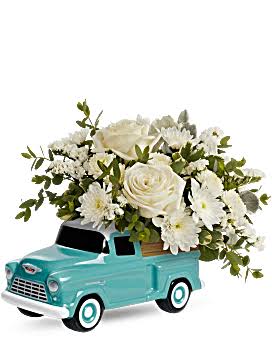 White flower arrangement in a turquoise toy truck planter
