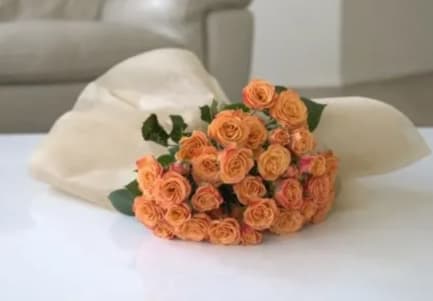 Bouquet of peach spray roses wrapped in white paper