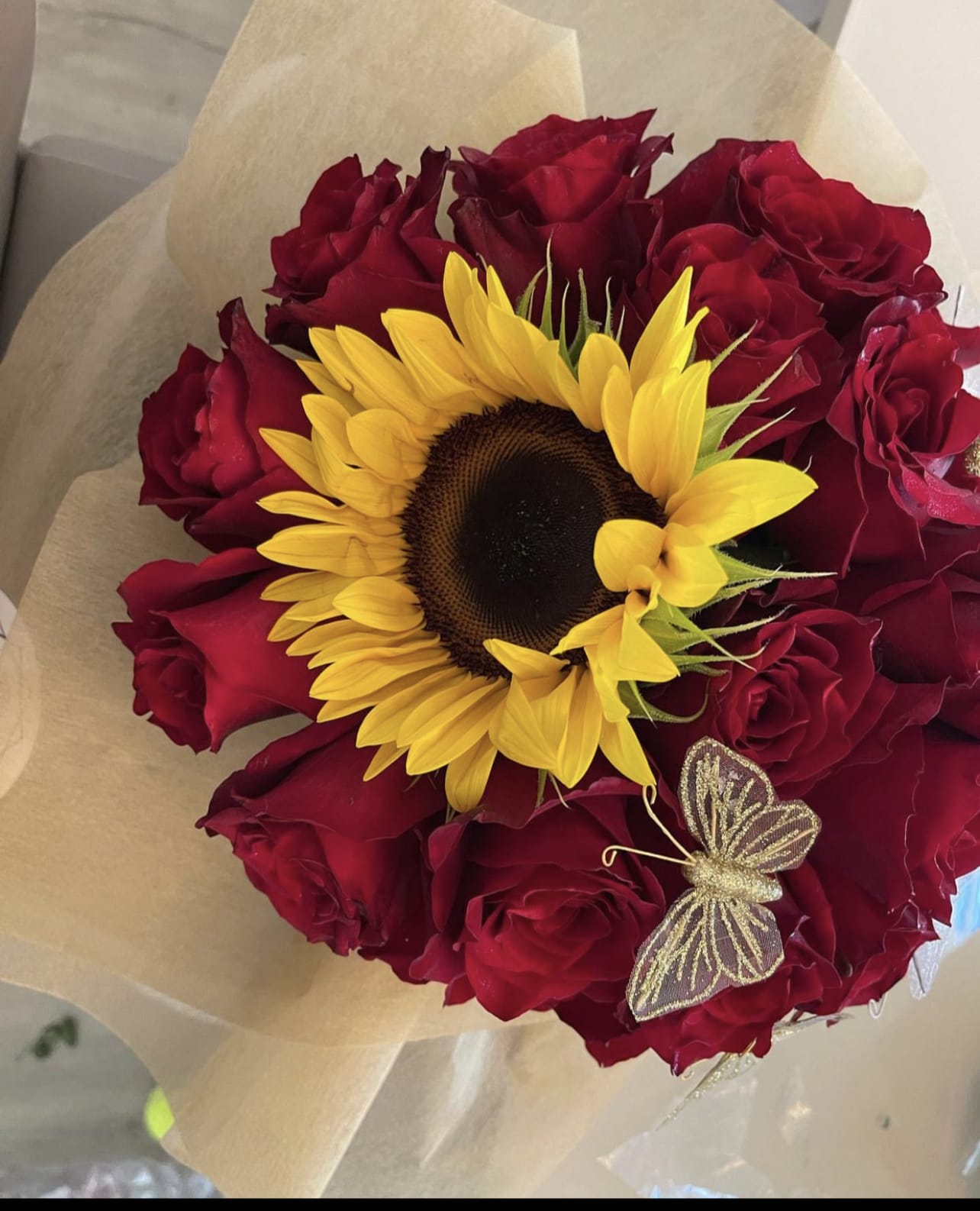 Bouquet of red roses with a yellow sunflower and butterfly decoration
