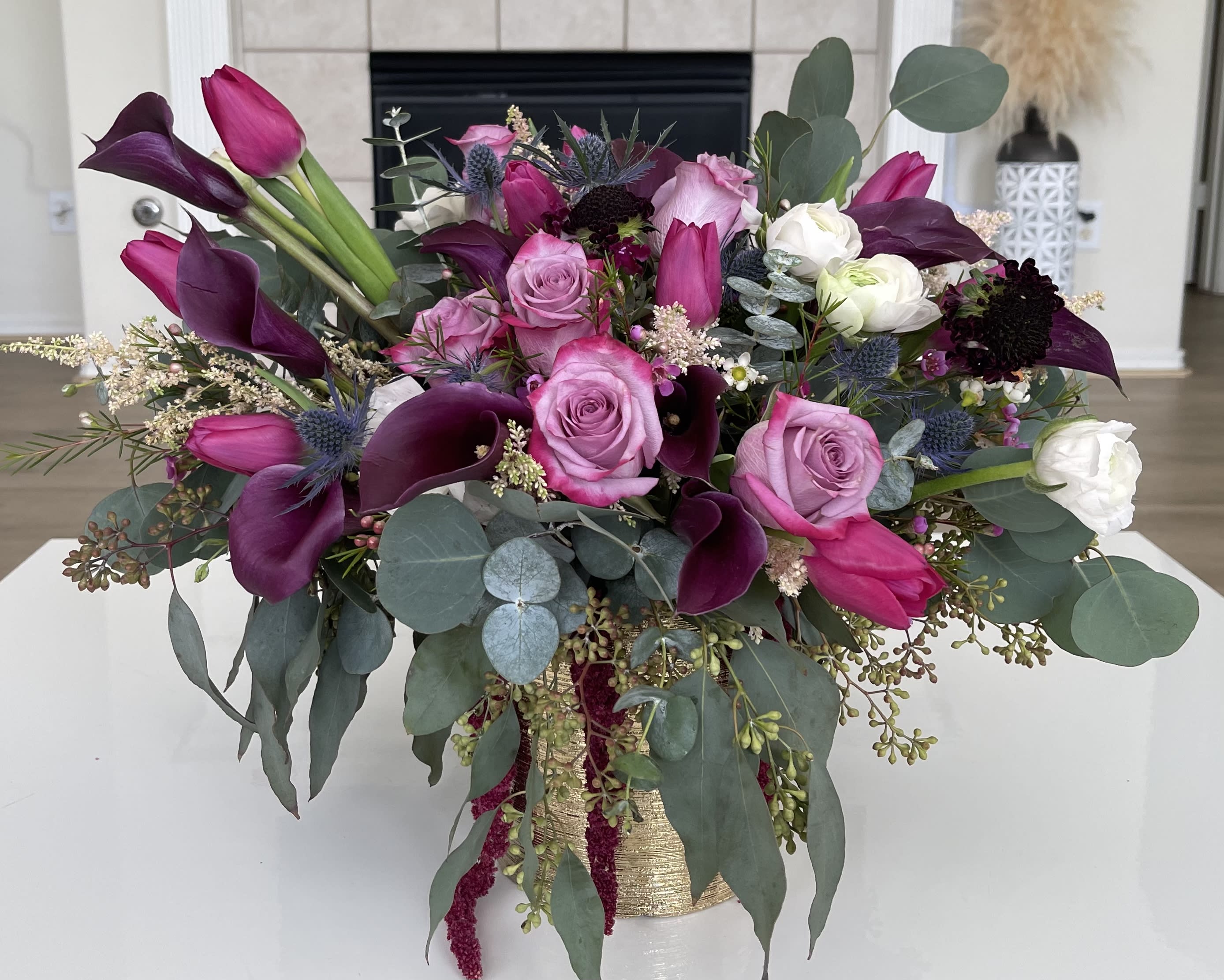 Bouquet of pink roses and dark purple calla lilies in a gold vase