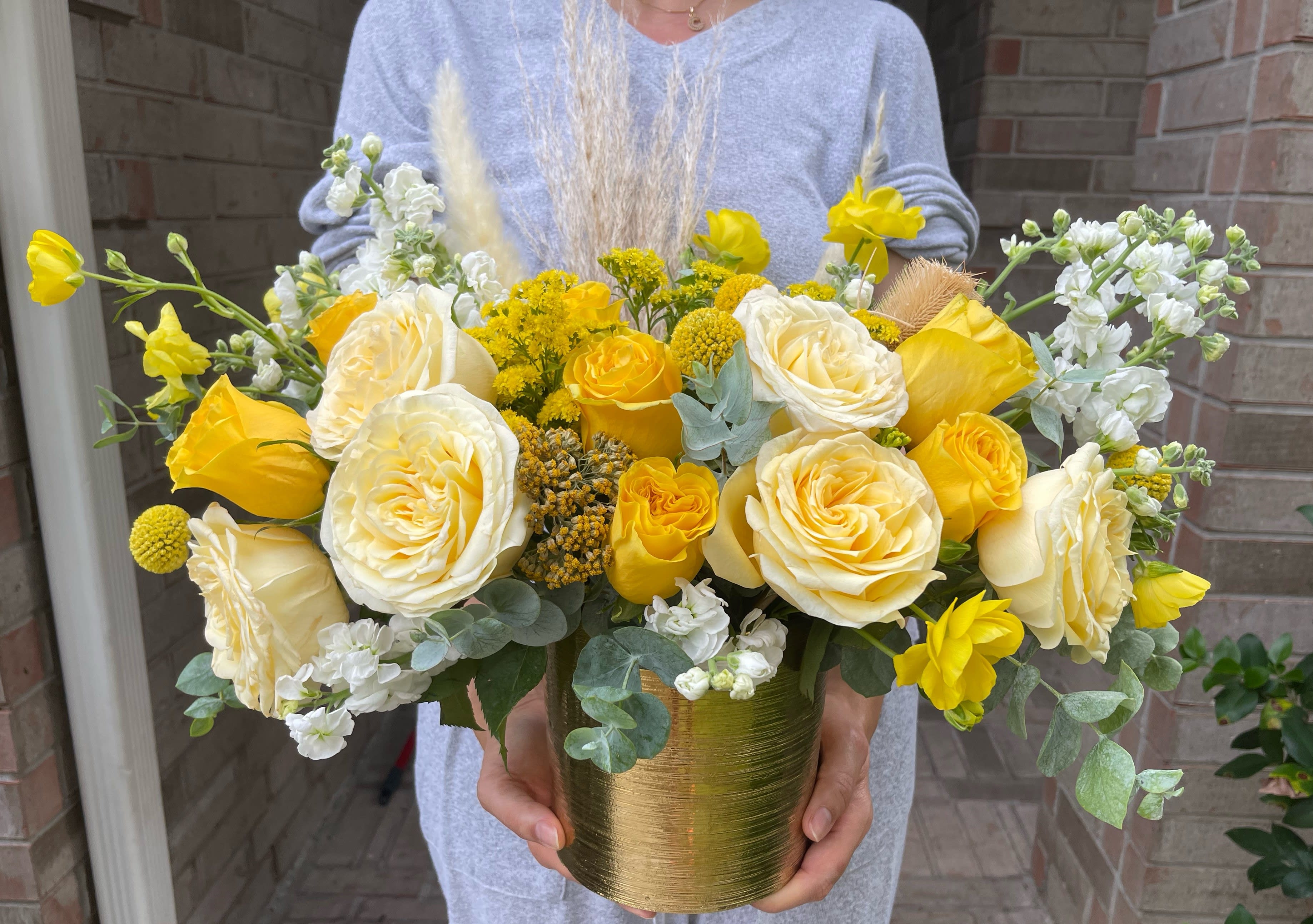 Yellow and white roses arranged in a gold vase