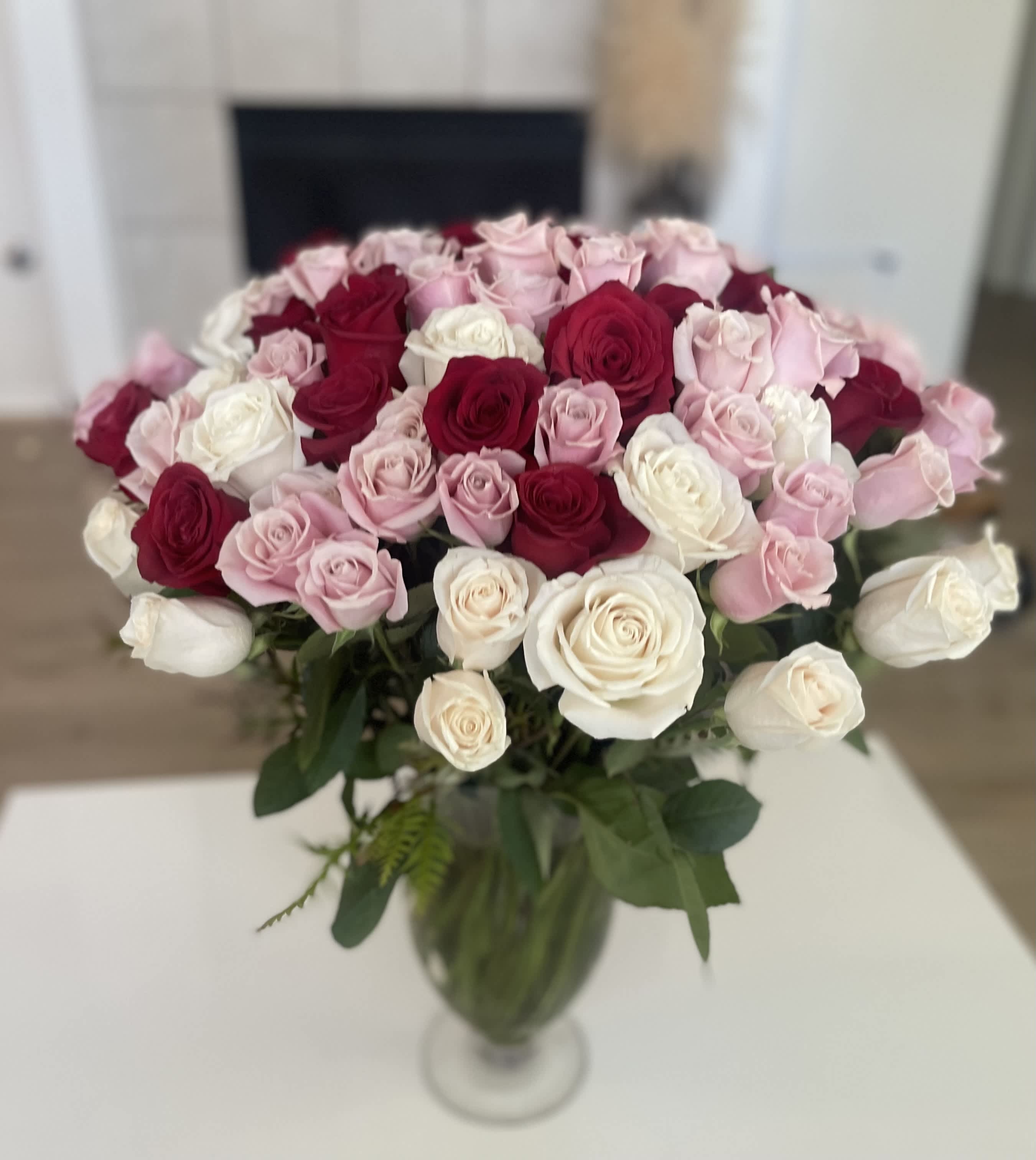 Bouquet of pink, red, and white roses in a clear glass vase