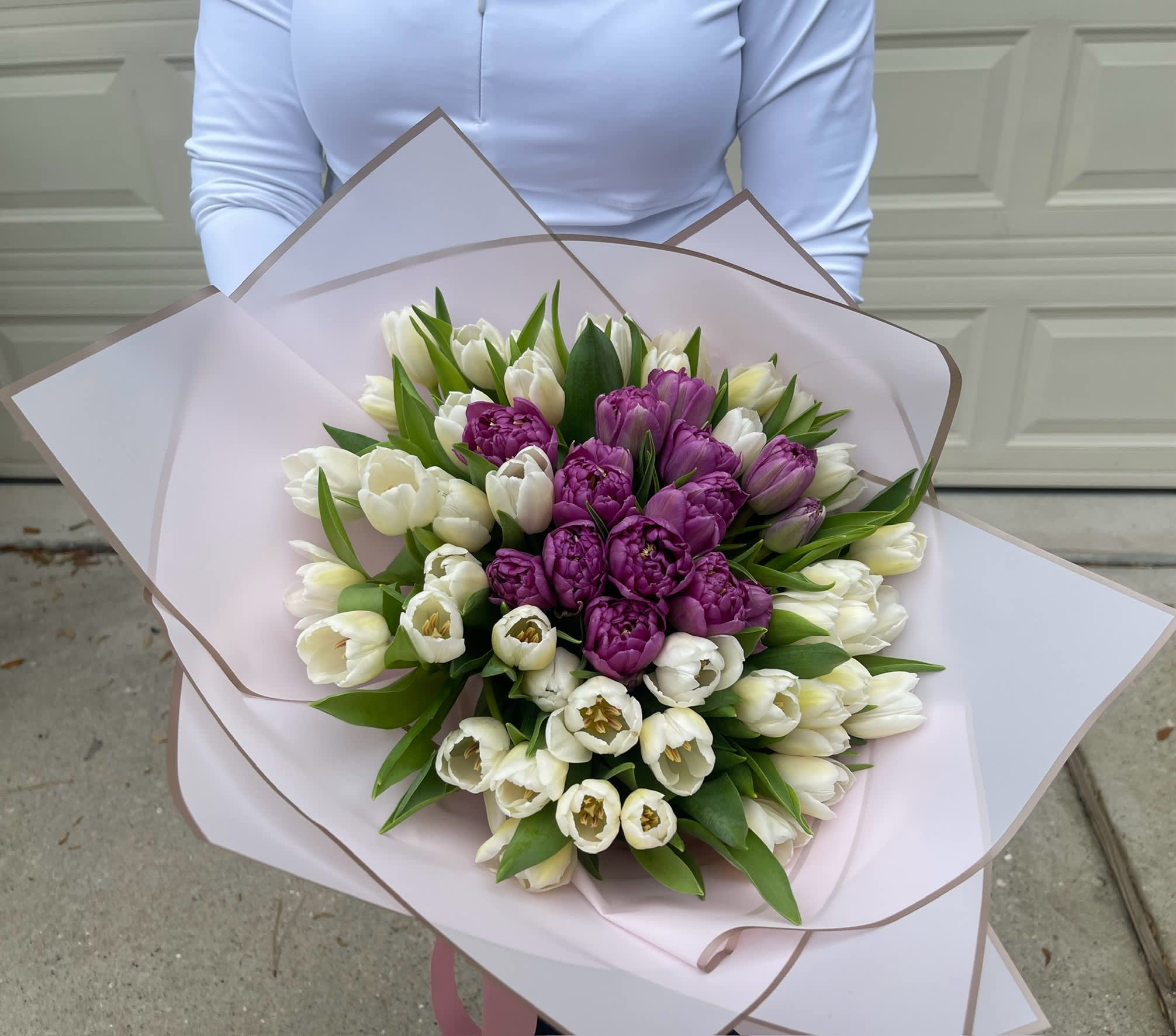 Bouquet of white and purple tulips wrapped in pale pink paper