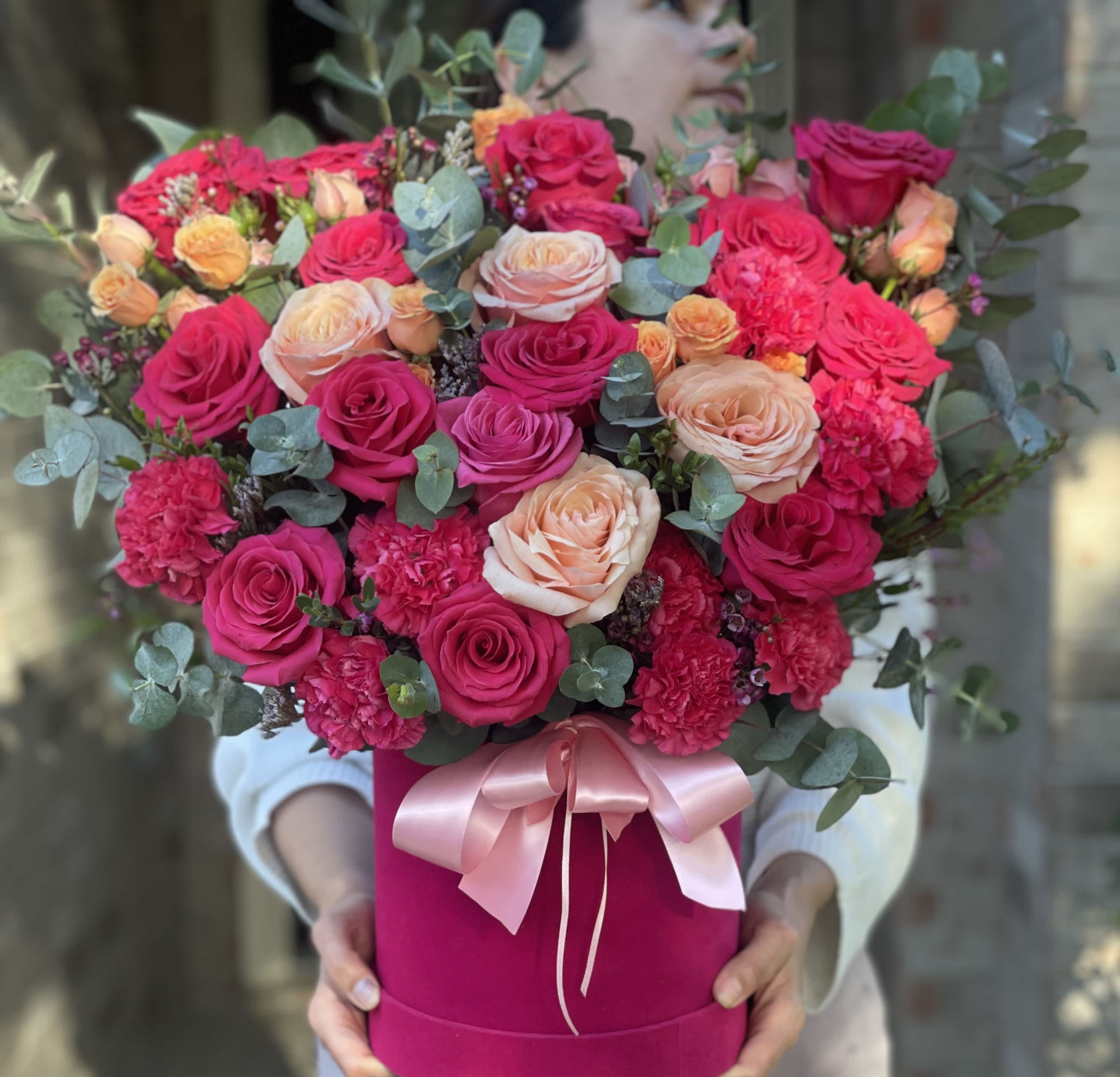 Bouquet of pink and peach roses in a magenta hat box with a pink ribbon