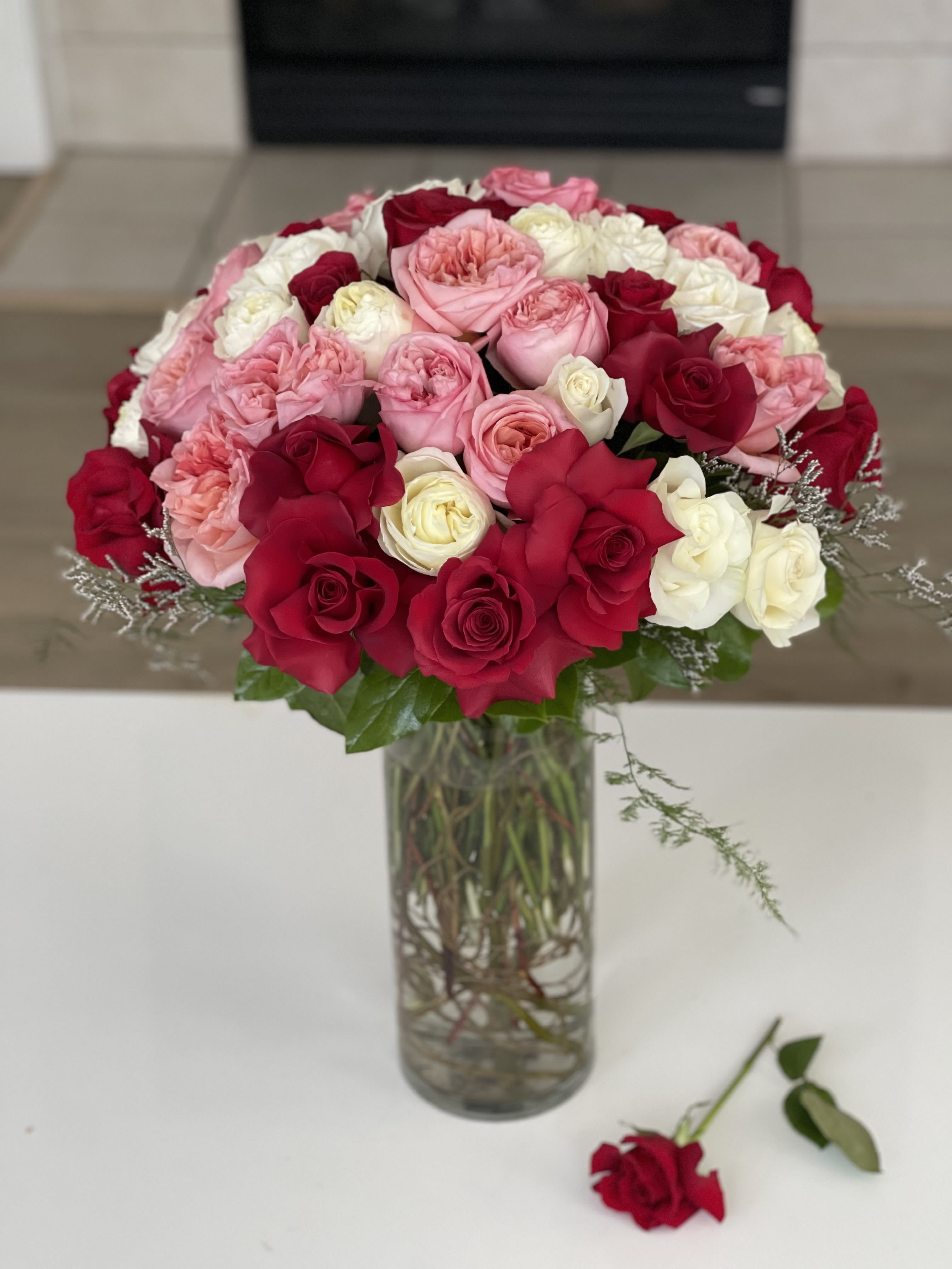 Bouquet of pink, red, and white roses in a clear glass vase