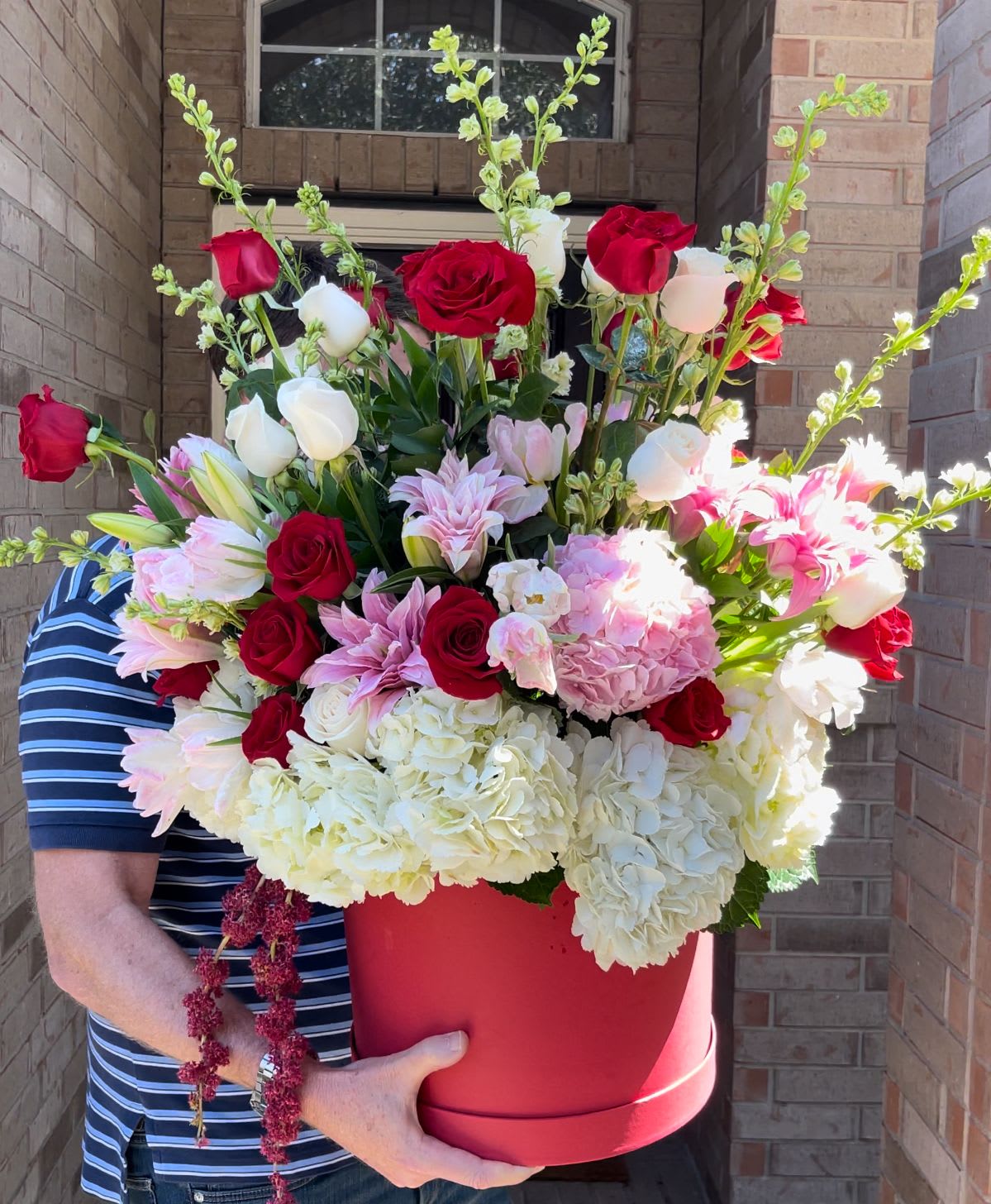 Large red hatbox arrangement with roses, hydrangeas, and lilies