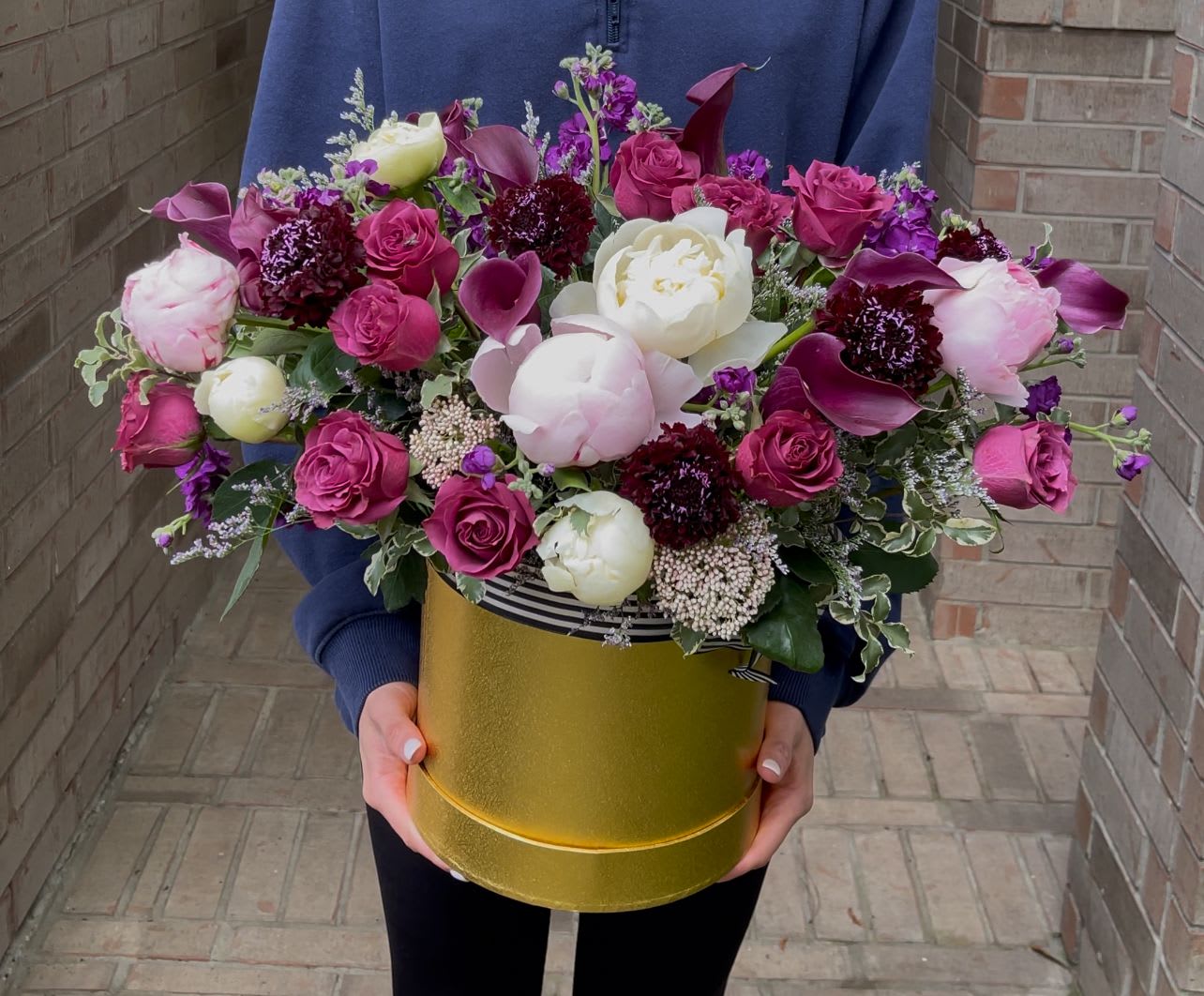 Large bouquet of pink and white flowers in a gold hatbox