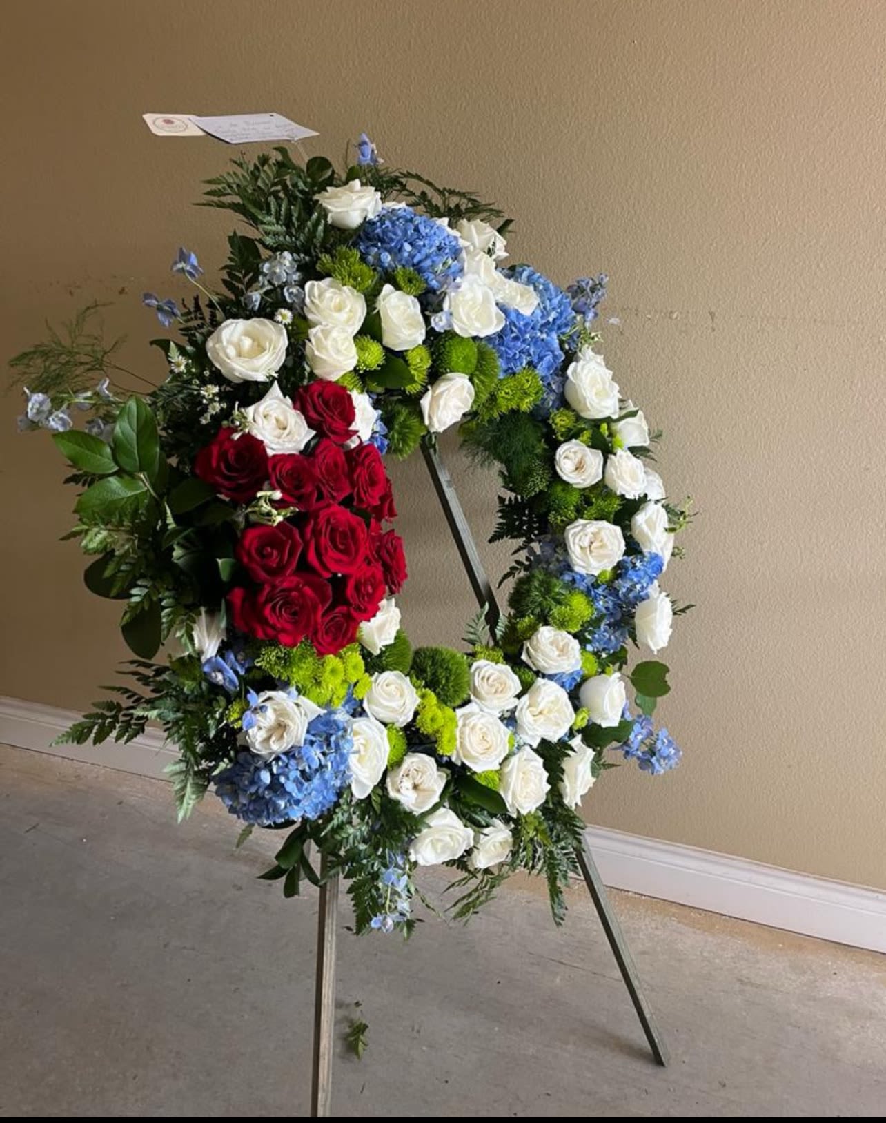 Large standing floral wreath with red, white, and blue flowers on an easel