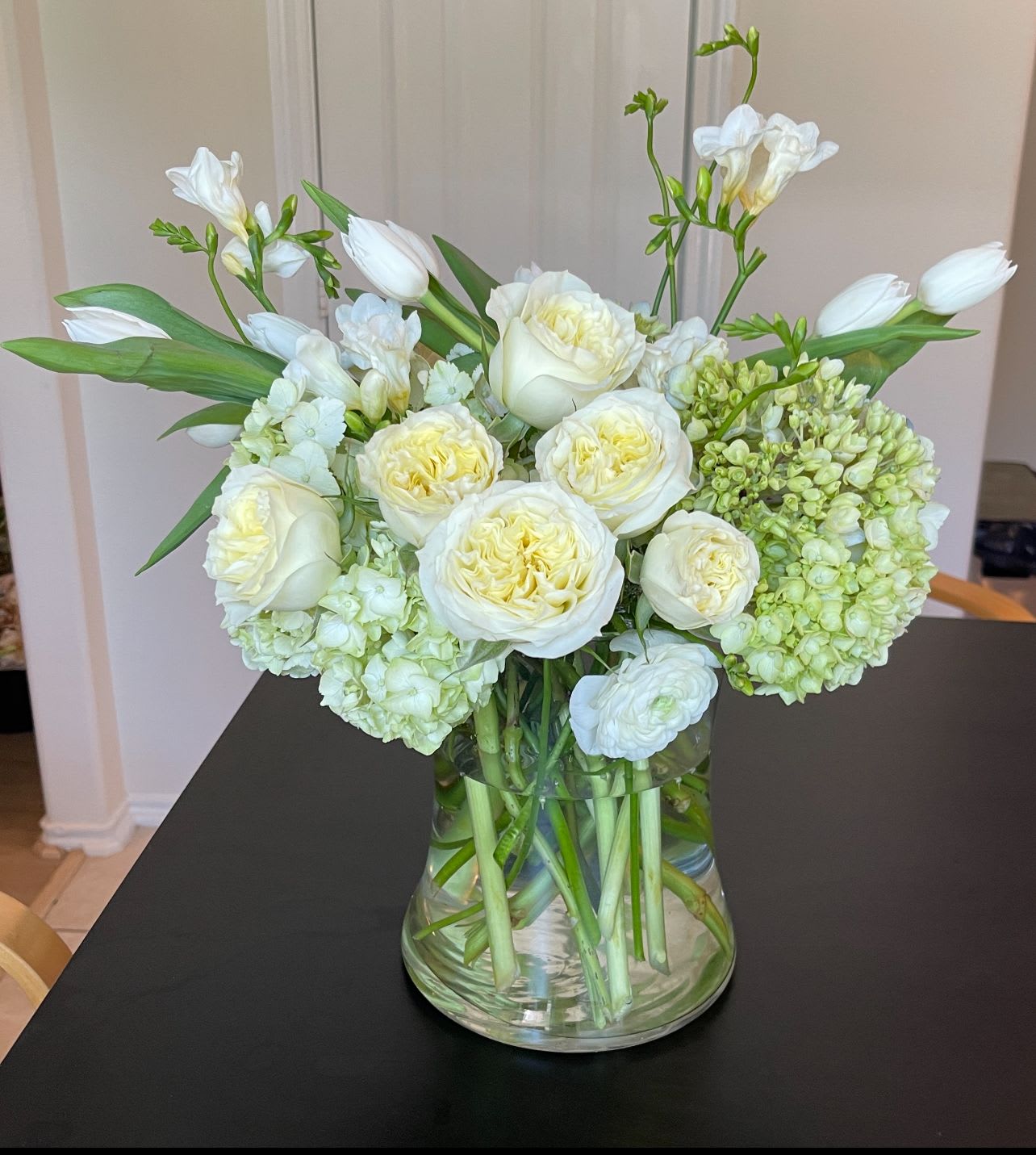 White roses and tulips arranged in a clear glass vase