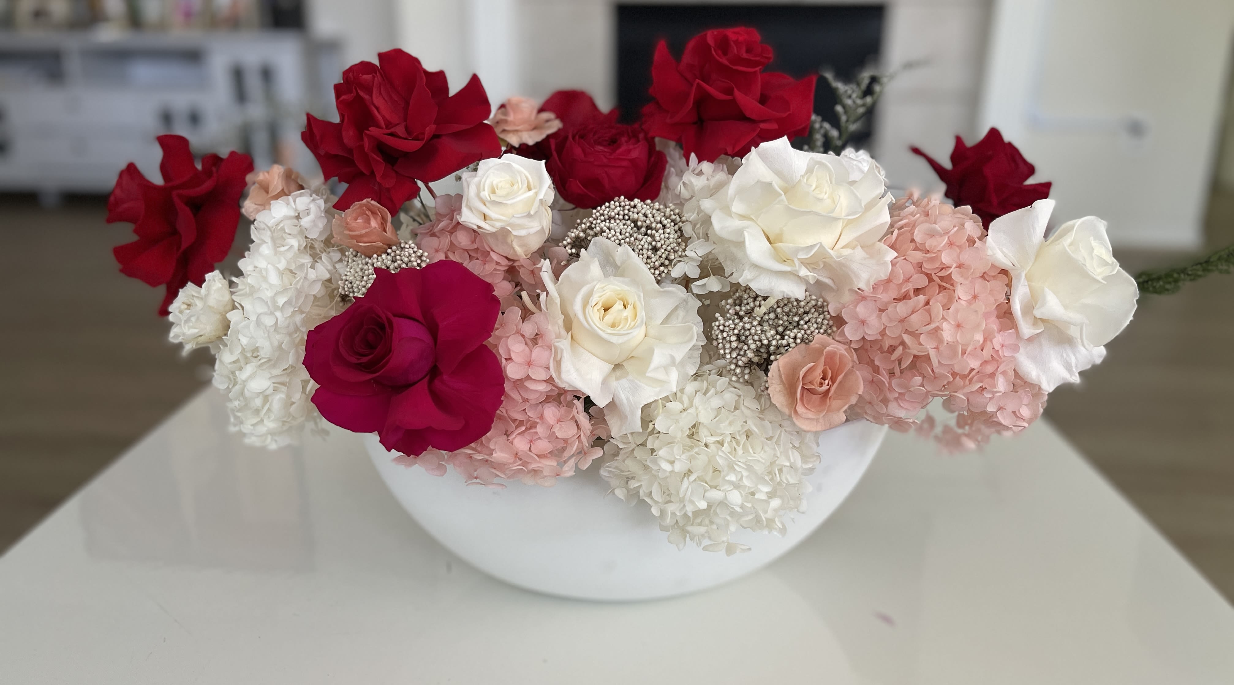 Red and white roses with pink hydrangeas in a white bowl