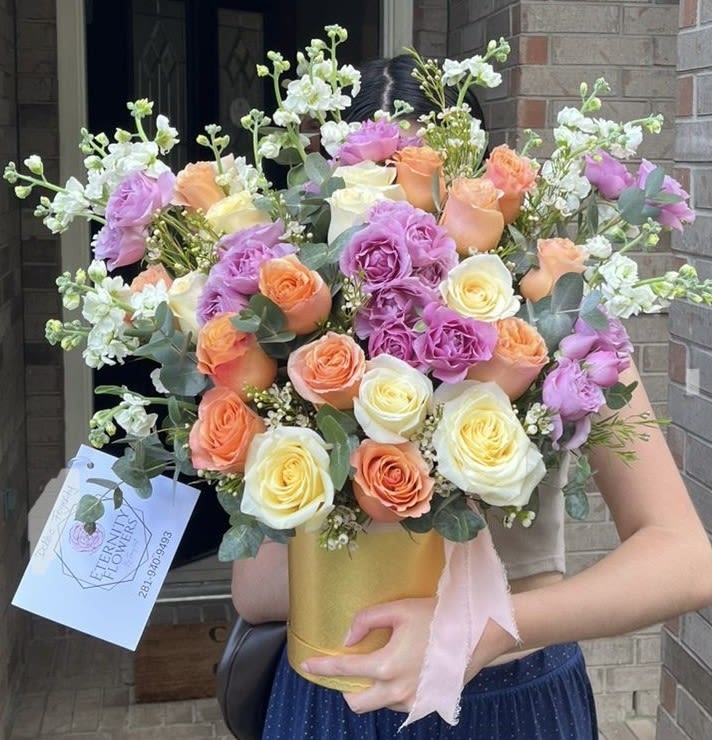 Bouquet of peach, lavender, and white roses in a gold vase