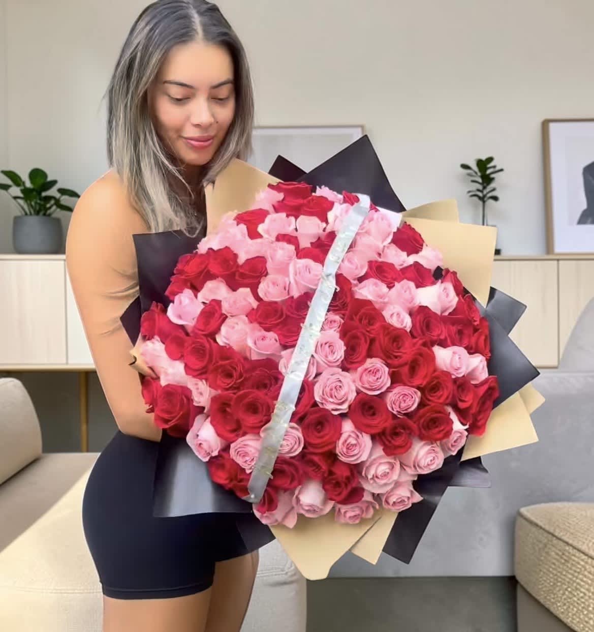 Large bouquet of red and pink roses wrapped in black and beige paper