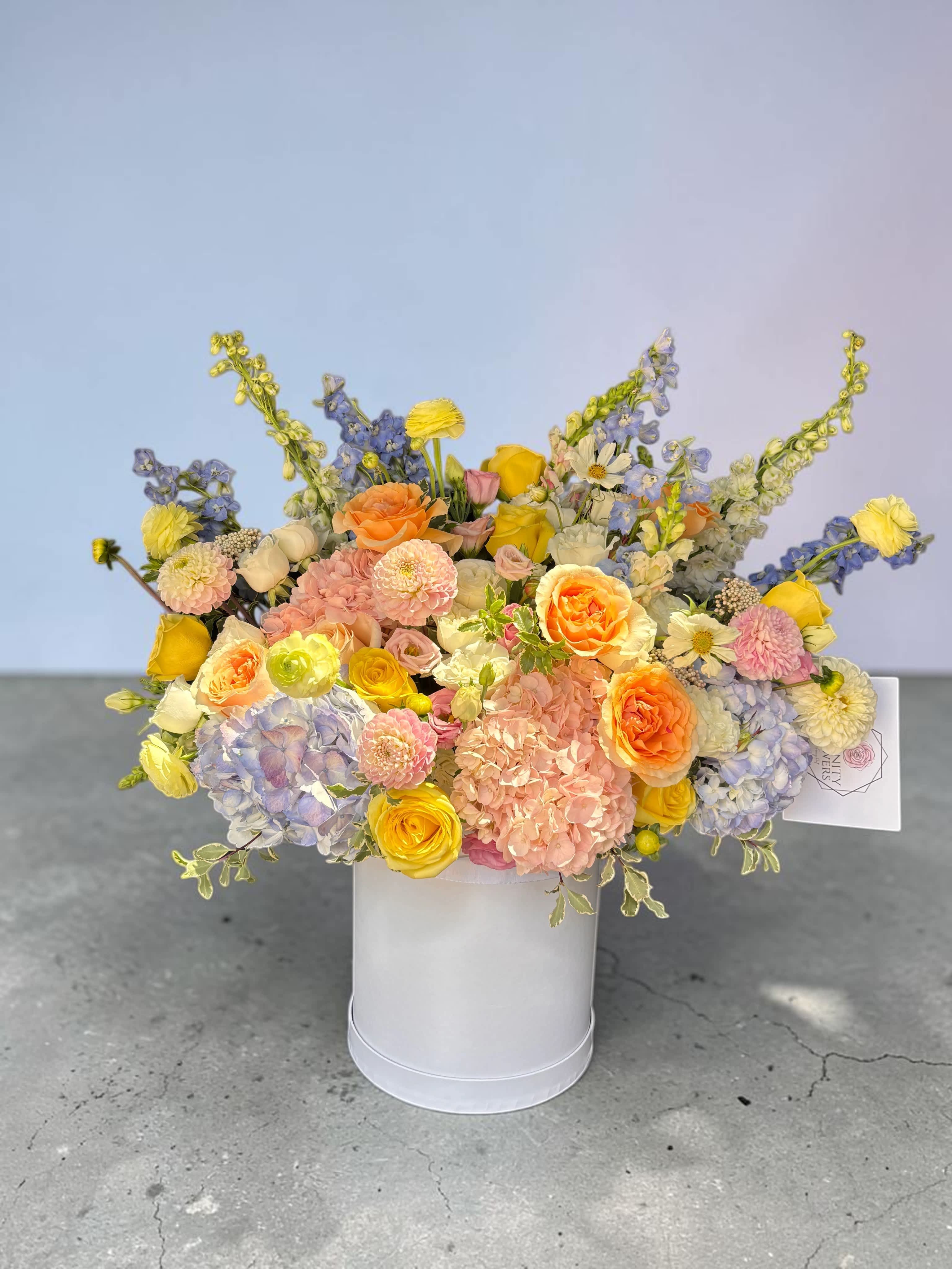 Mixed pastel bouquet in a white hatbox with roses and hydrangeas