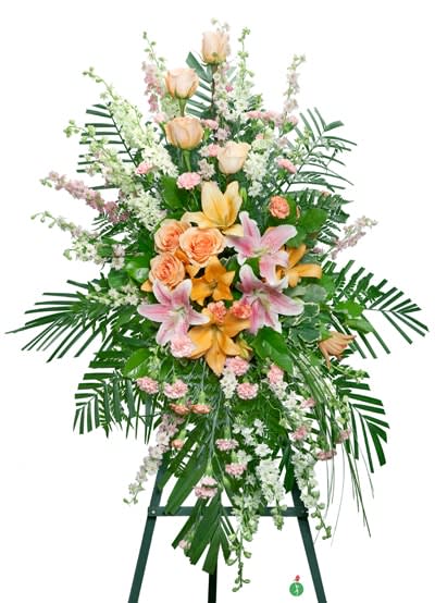 Tall standing spray of peach roses, pink lilies, and mixed flowers on a green easel