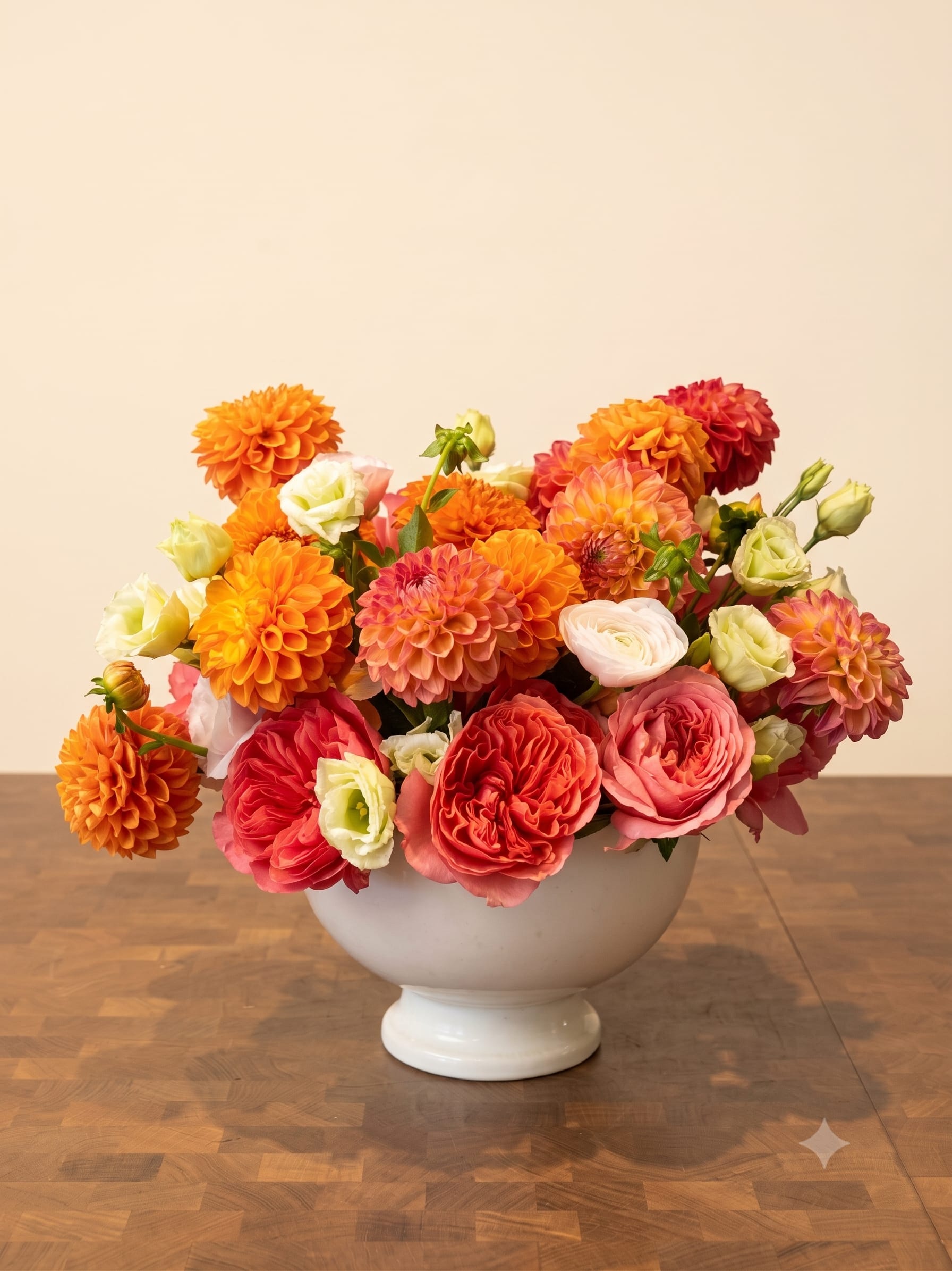 BP130 - Sweet Tangerine Dream - A luxurious, textured arrangement featuring a vibrant palette of coral, bright orange, and creamy whites. This natural garden-style design is packed with garden roses, vibrant dahlias, and delicate lisianthus. Arranged elegantly in a classic white vase.  Seasonality: Dahlias (available summer/fall) 